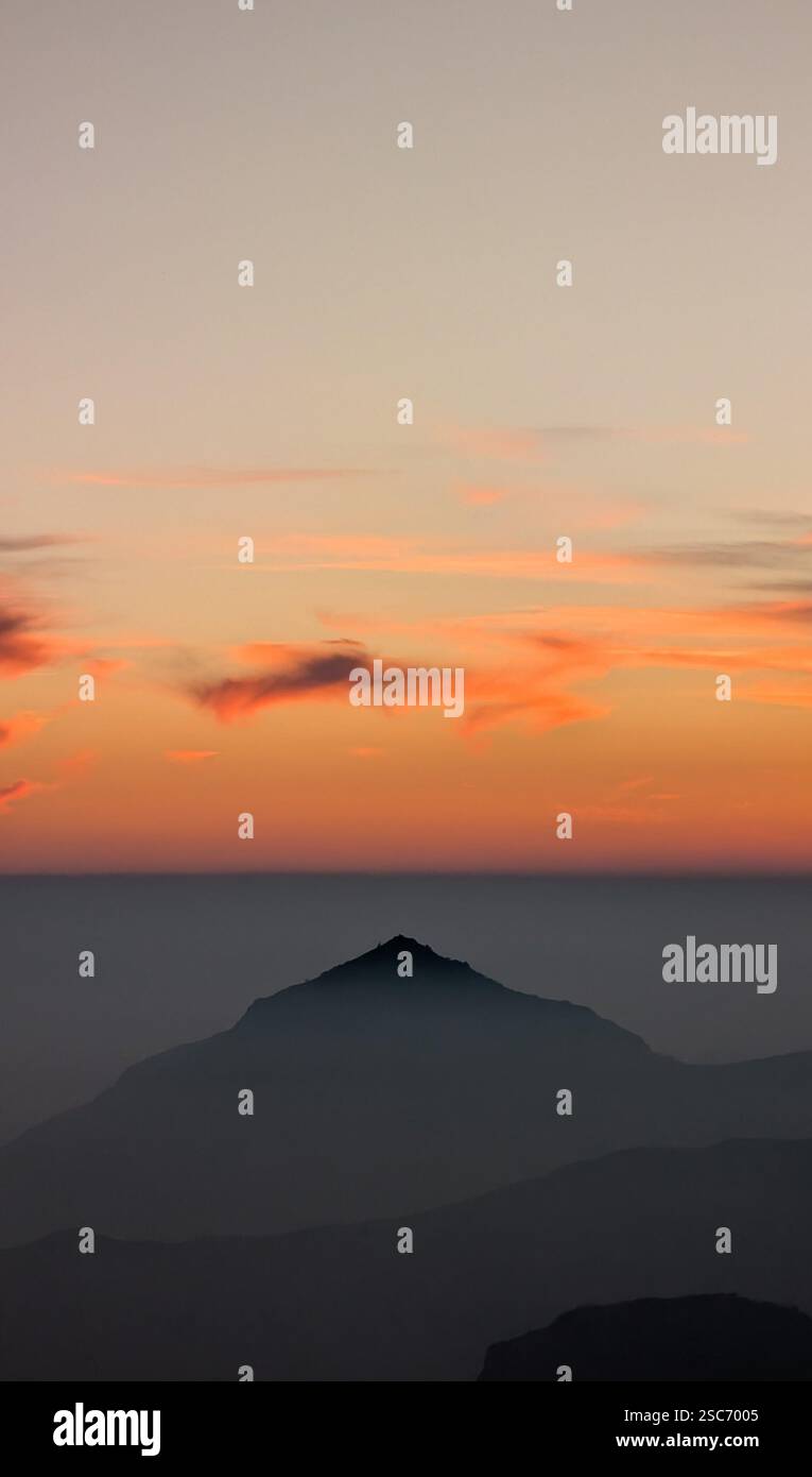 beautiful sunset with vibrant colors behind a sharp-peaked mountain - Smartphone Captured Stock Image