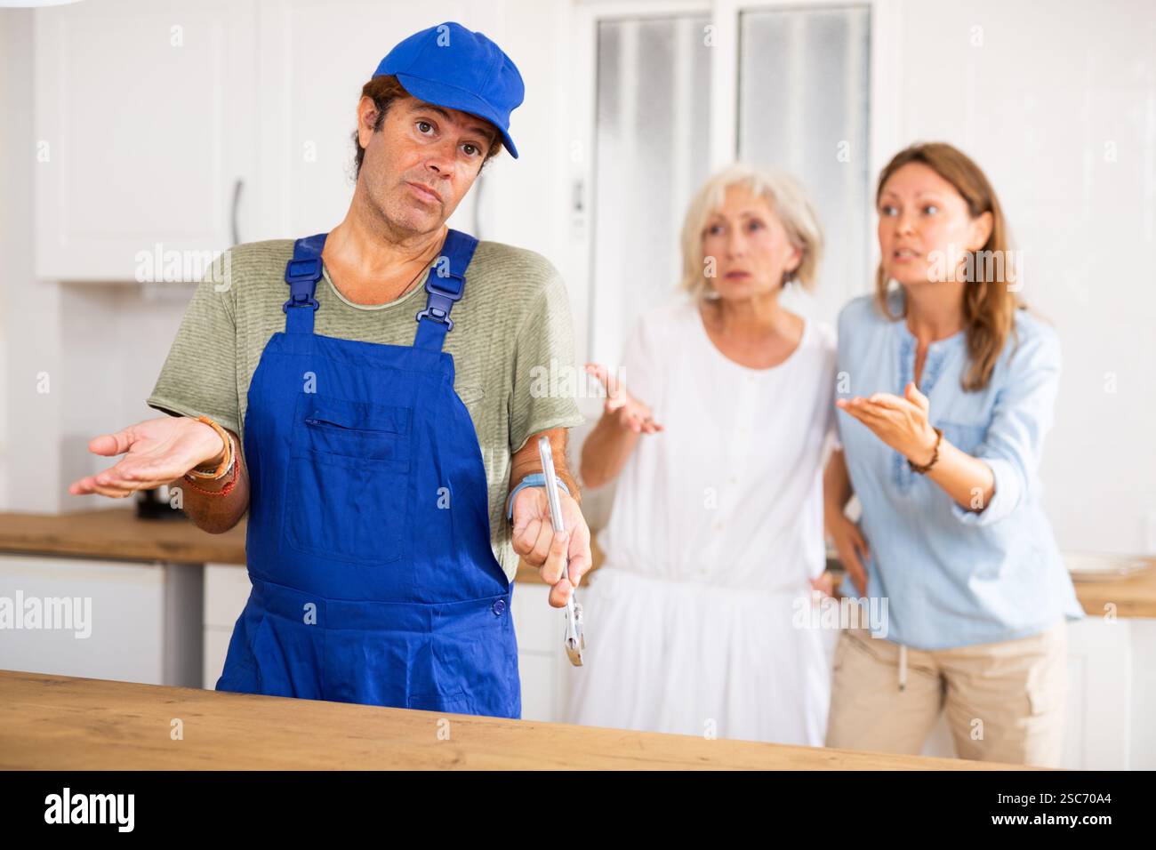 Kitchen Inattention Inattentive plumber in uniform spreading his arms to the sides while ...