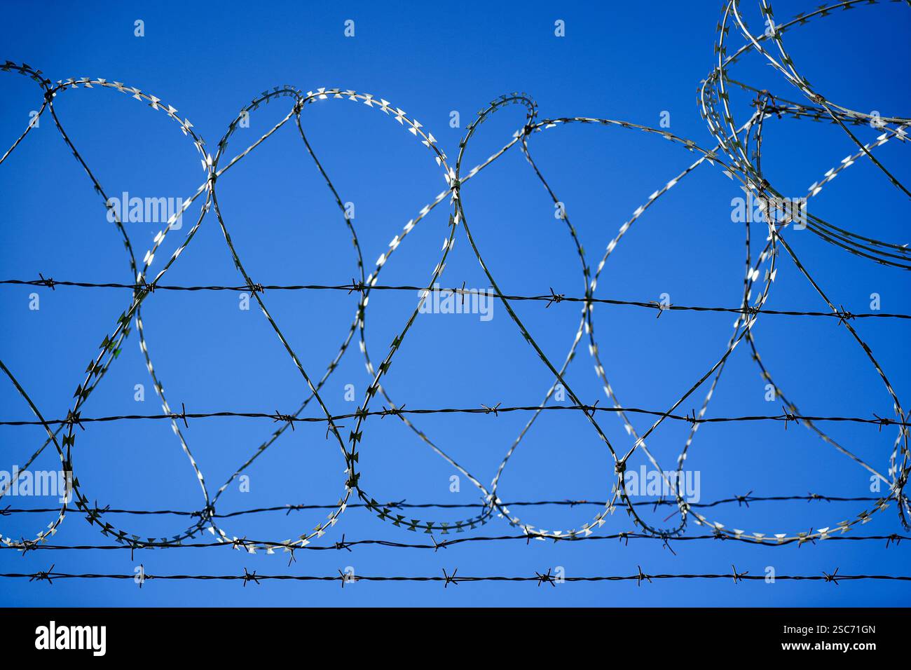 Barbed wire fence against blue sky Stock Photo