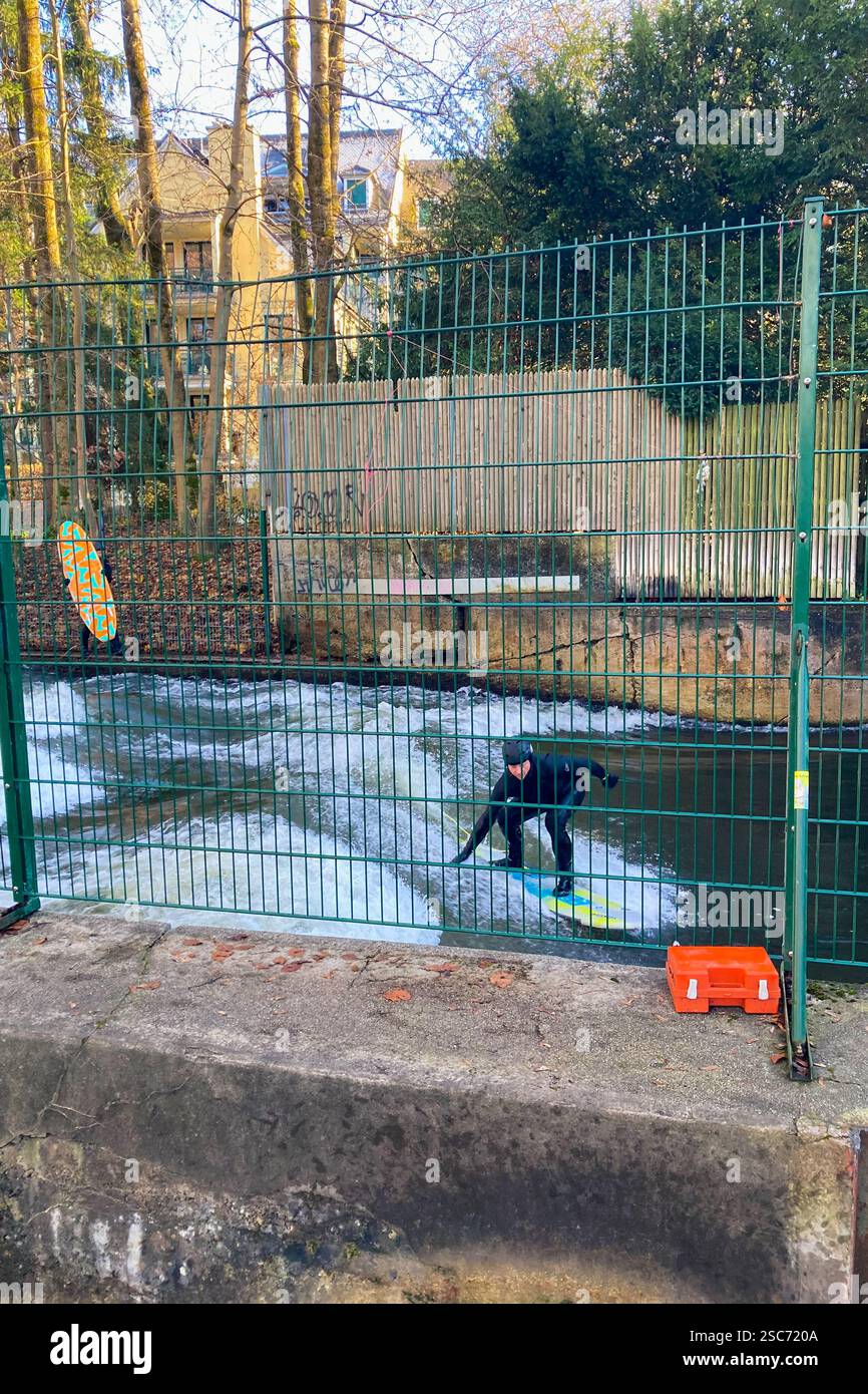 MUNICH, GERMANY - DECEMBER 2, 2024: Surfers on Eisbach river in the English garden in Munich, Bavaria - Smartphone Captured Stock Image