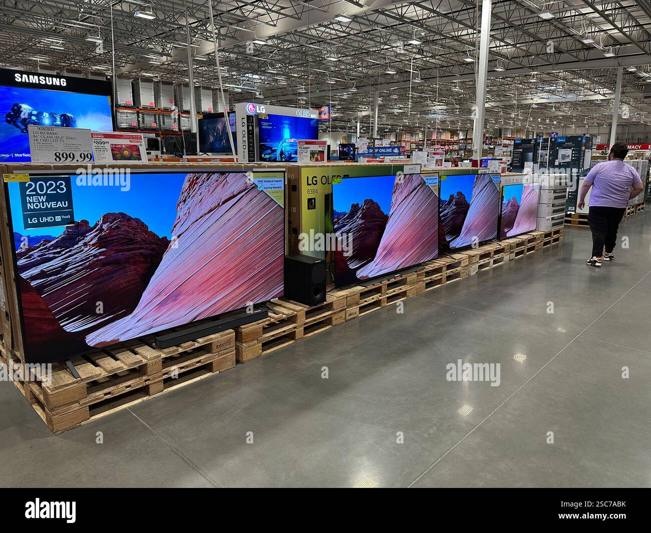 A shopper passes by a line of large-screen televisions on display in a ...