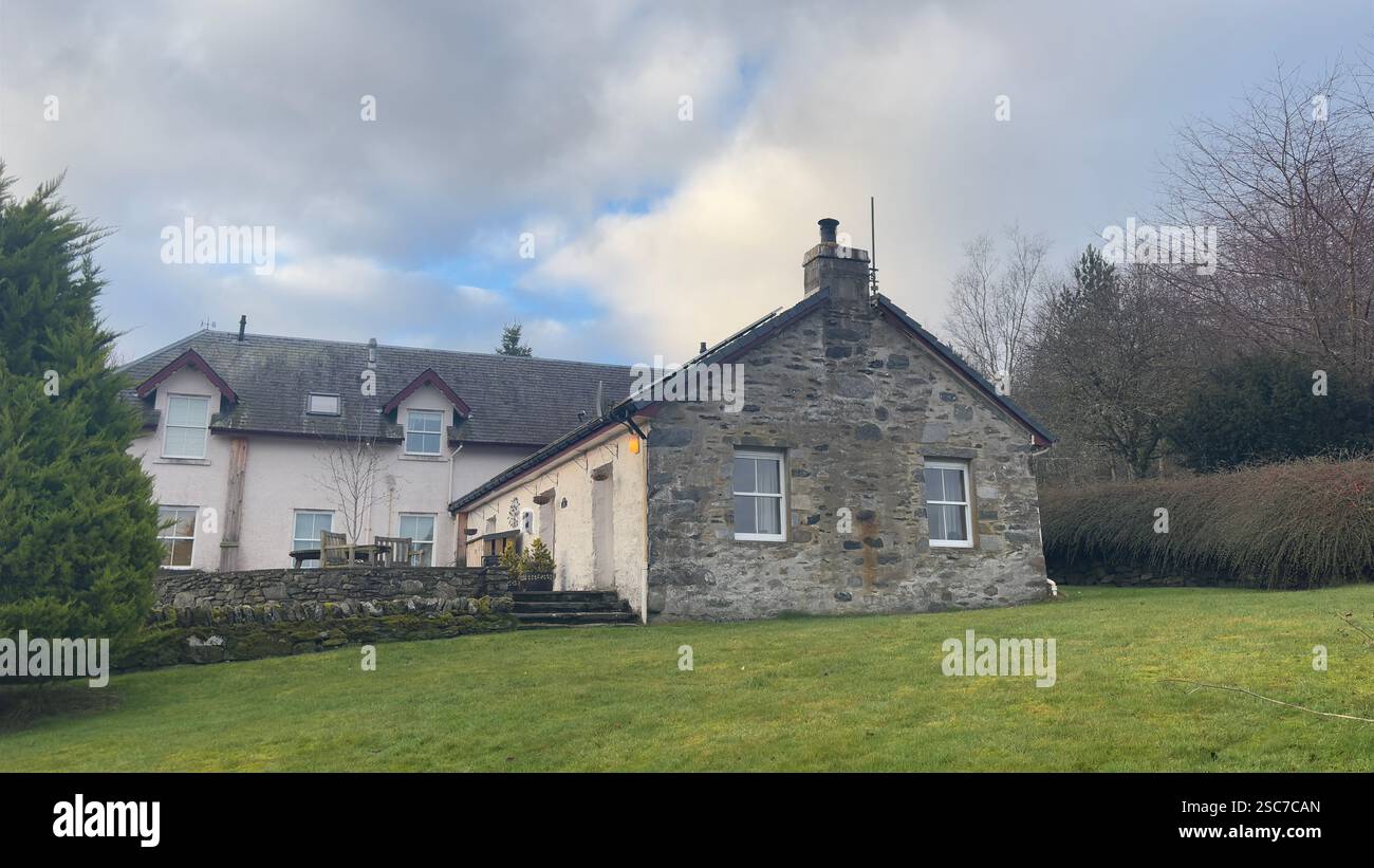 Traditional Scottish farm cottage with solar panels on the roof. White painted stone. Garden aspect. Modern croft - Smartphone Captured Stock Image