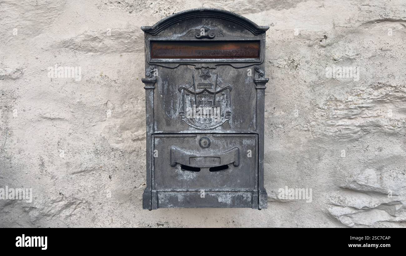 Old post box on a white wall. Letter box made of metal. Cast iron old vintage item - Smartphone Captured Stock Image