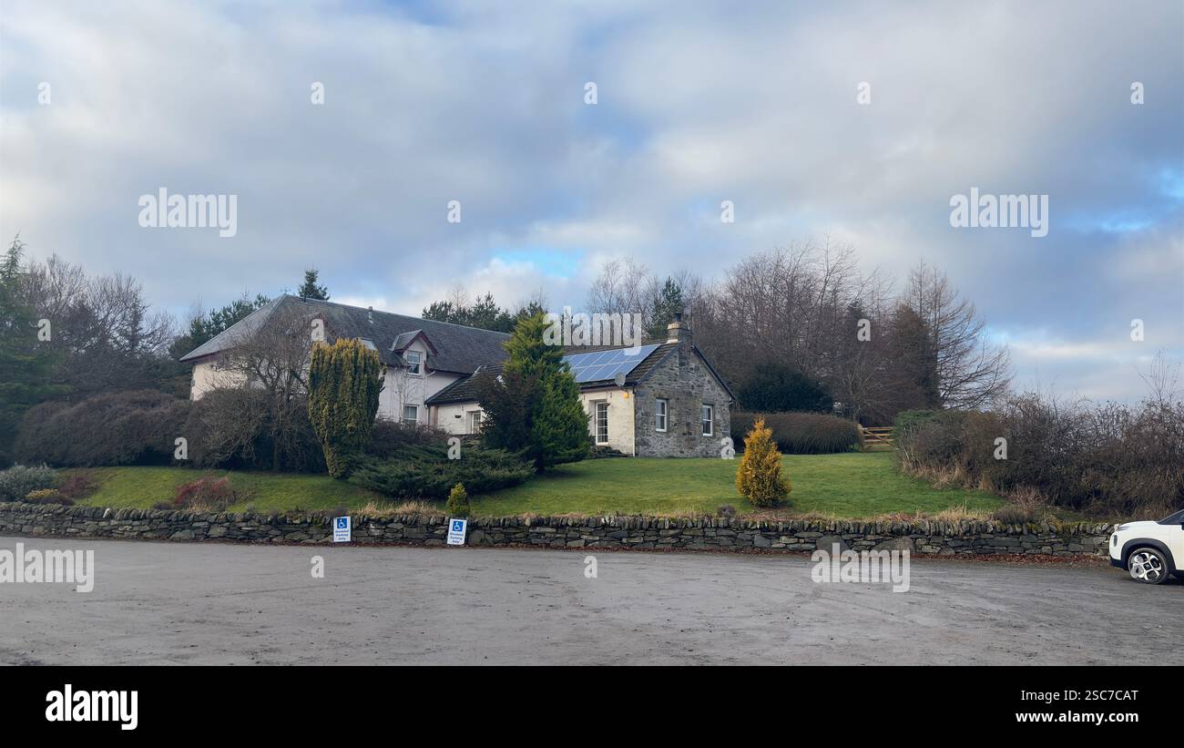 Traditional Scottish farm cottage with solar panels on the roof. White painted stone. Garden aspect. Modern croft - Smartphone Captured Stock Image