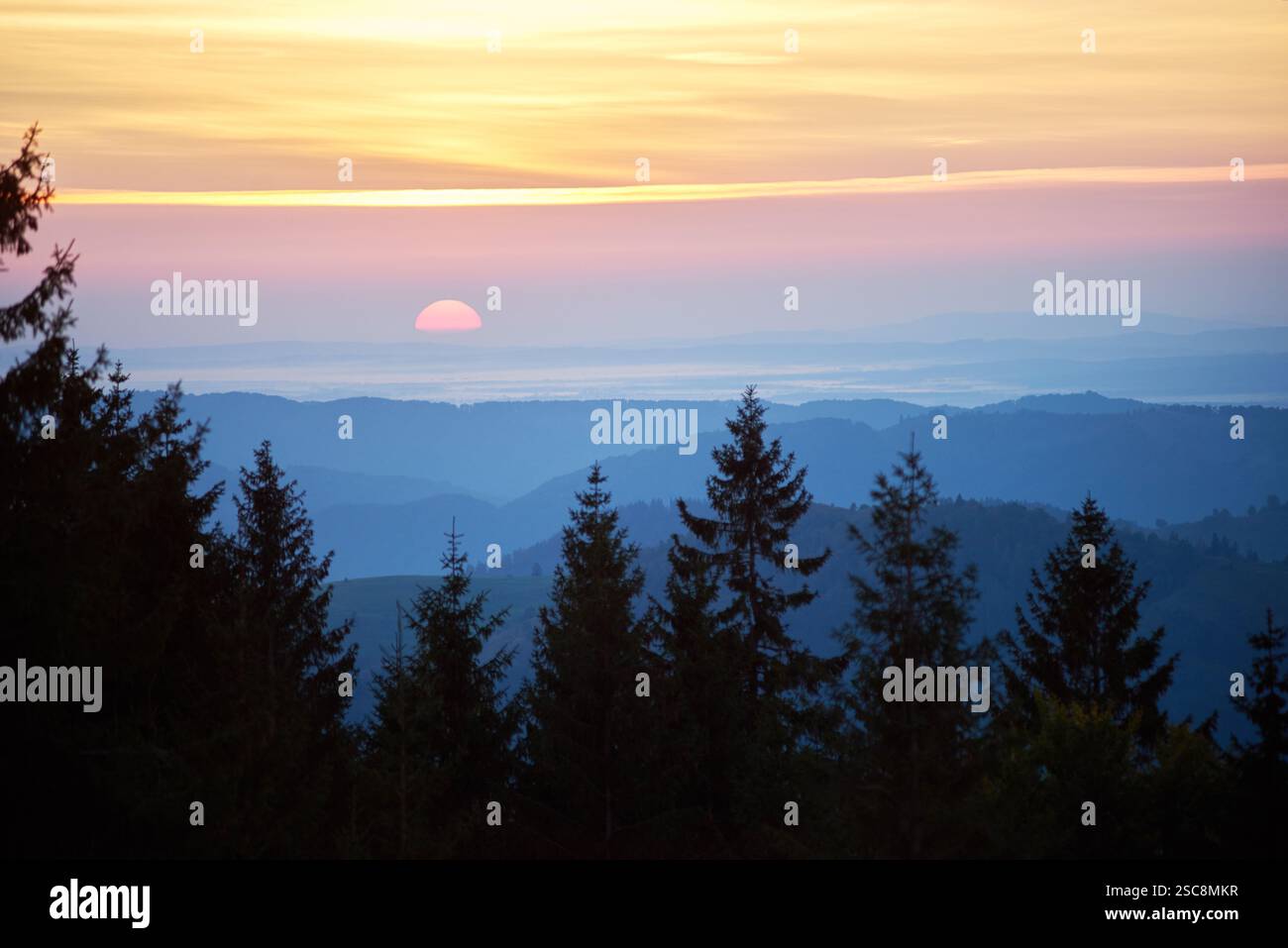 Vivid sunset with sun casting warm gradient of yellow, orange, and pink ...