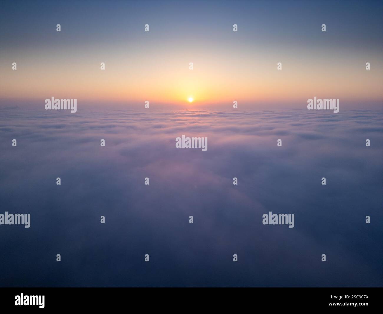 Sunrise above a vast sea of clouds. The golden light gently illuminates ...