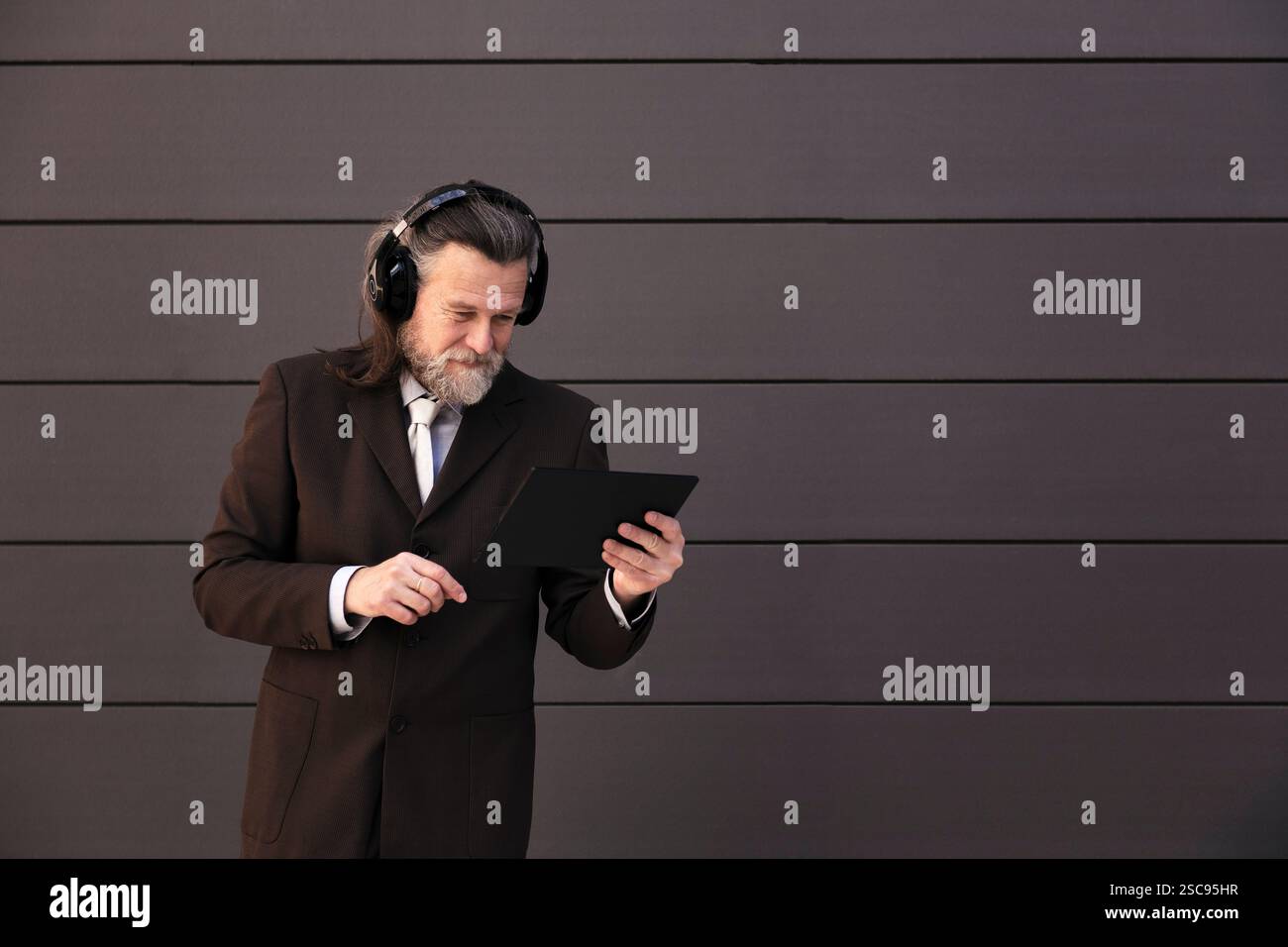 elegant mature man using tablet and headphones Stock Photo