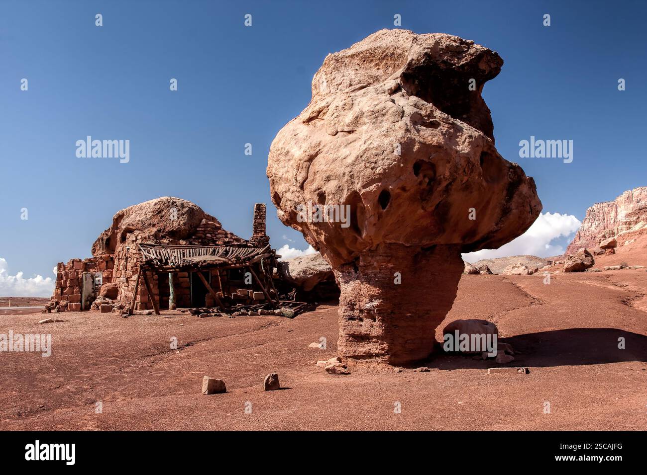 A large rock with a hole in it sits in the desert. There is a small ...