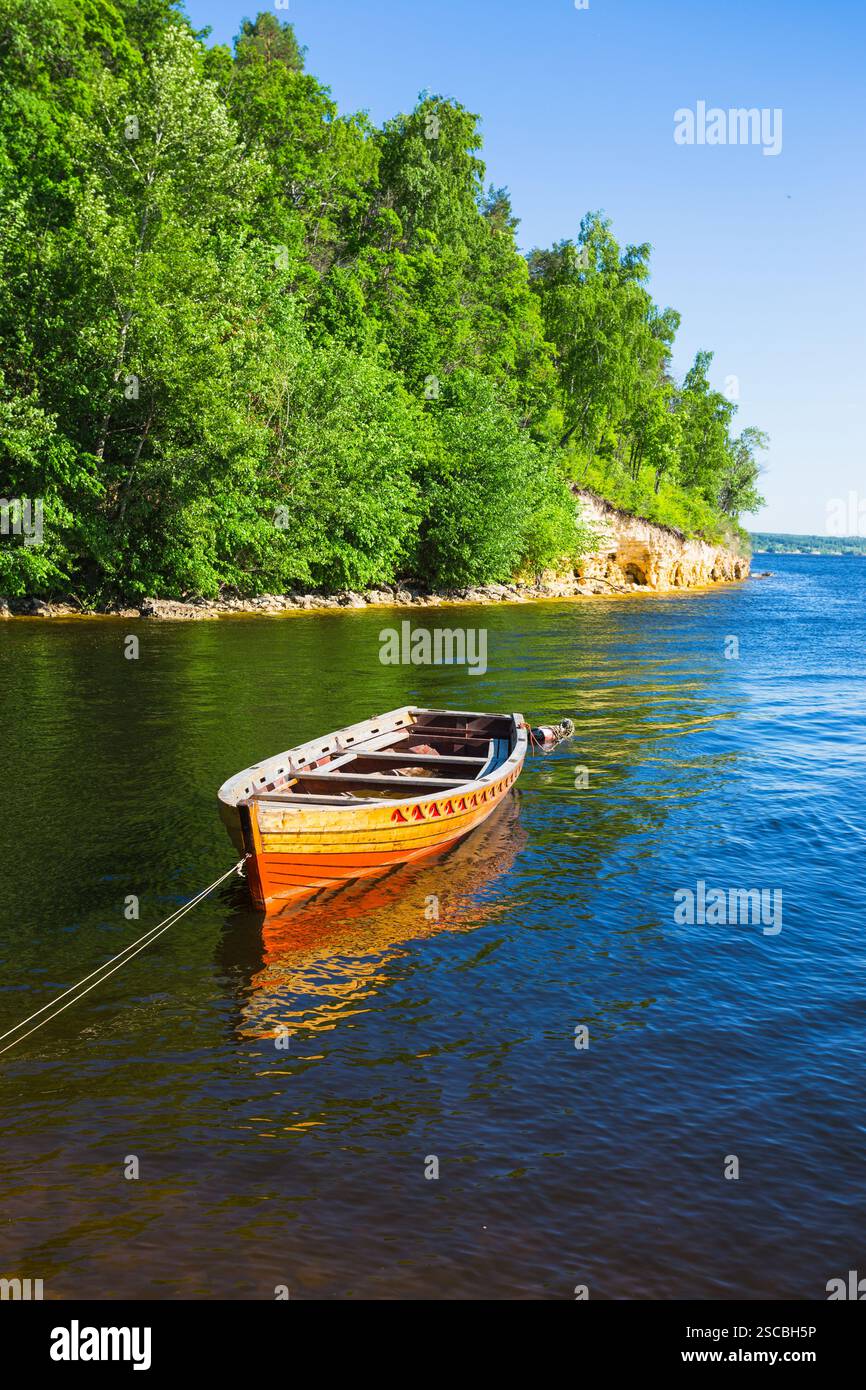 wooden boat on the river bank on forest background and blue sky ...
