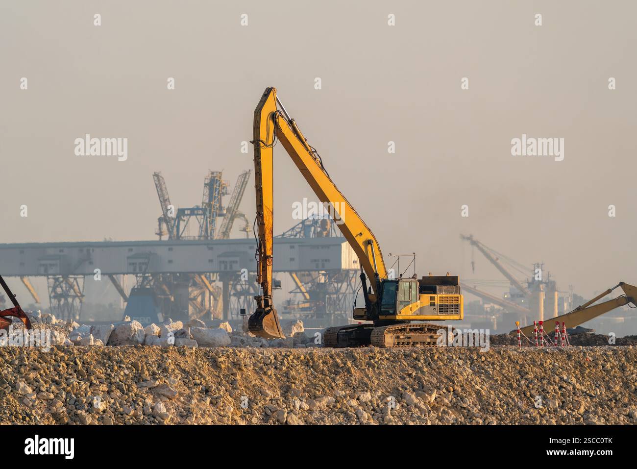 A large digger is doing filling works in the harbour Stock Photo