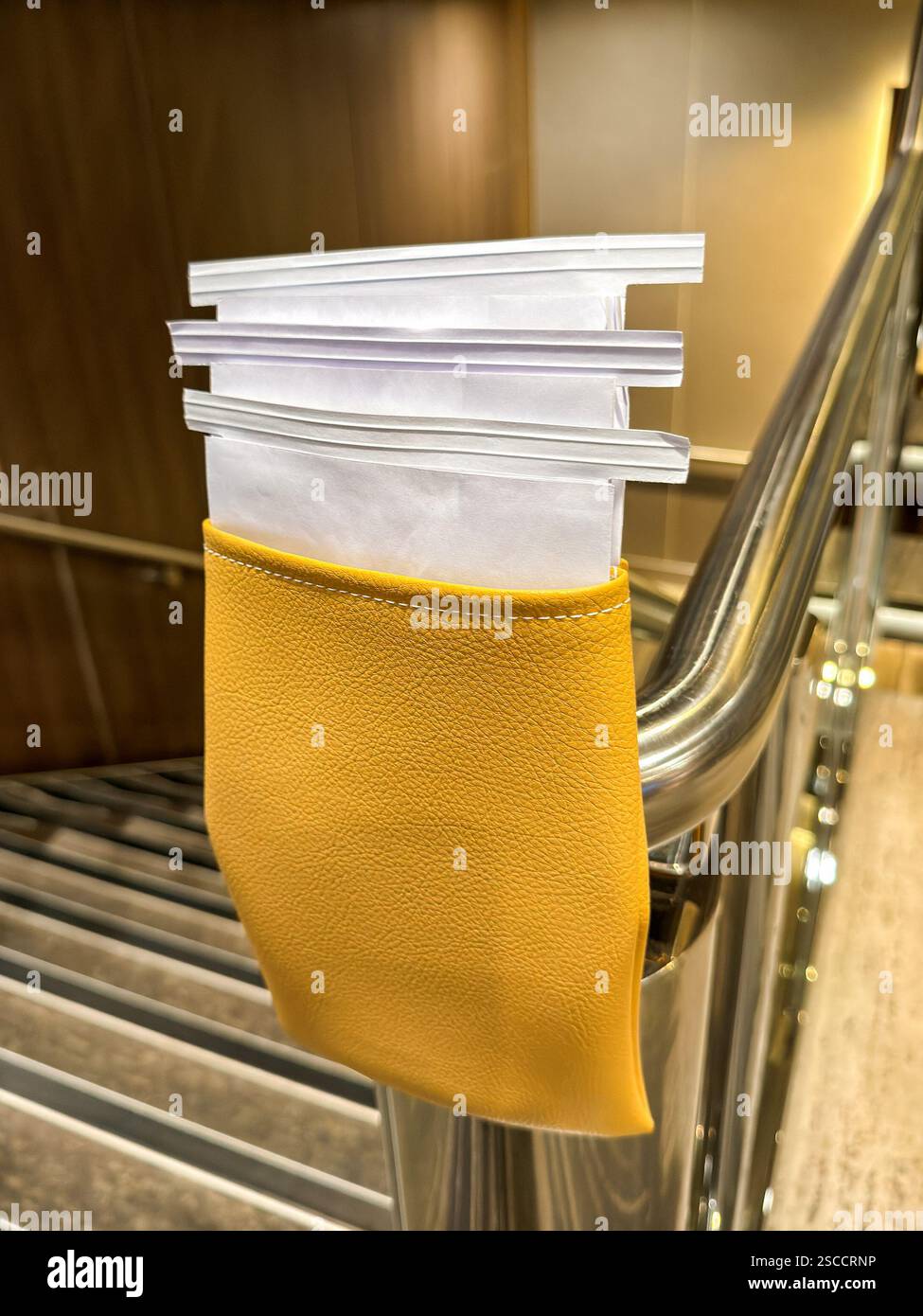 Sick bags in a container attached to a stair-rail for use by passengers ...