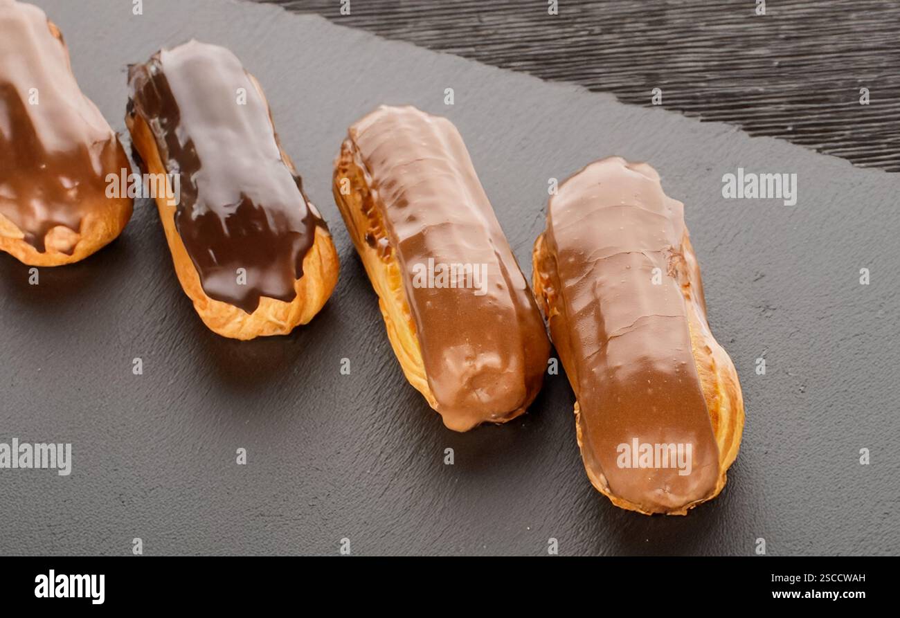 Three sweet eclairs on a slate stone, close-up. Stock Photo