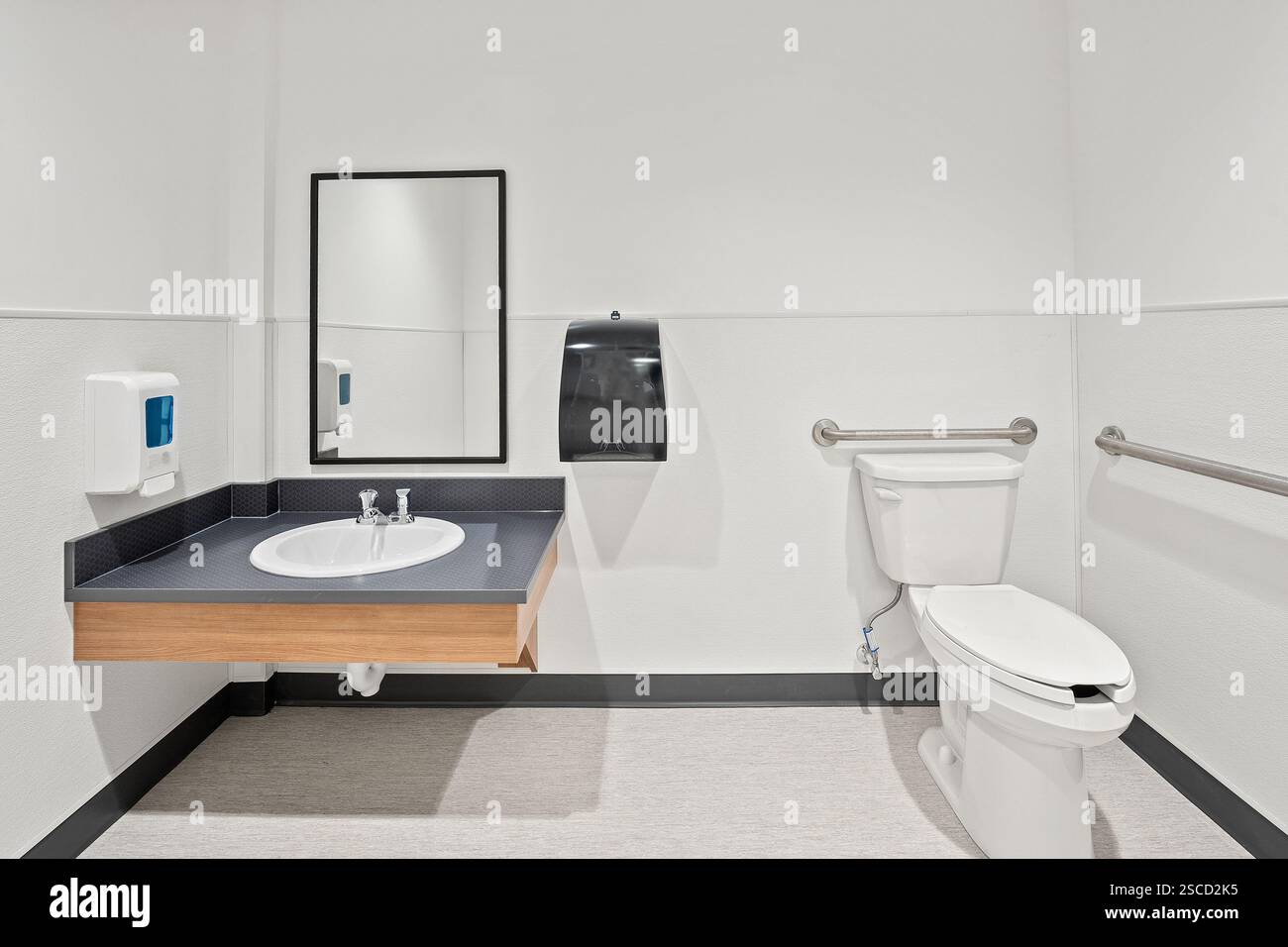 A bathroom with a sink, toilet, and mirror. The toilet is white and has a lid Stock Photo - Alamy