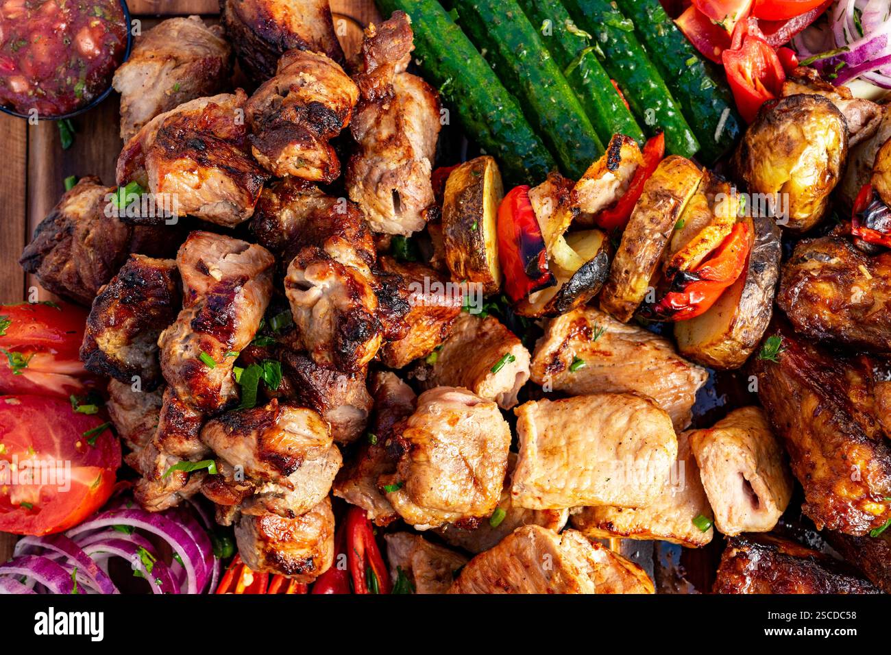A colorful assortment of grilled meats accompanied by fresh vegetables and salsas. Perfectly prepared, this festive dish showcases a variety of flavor Stock Photo