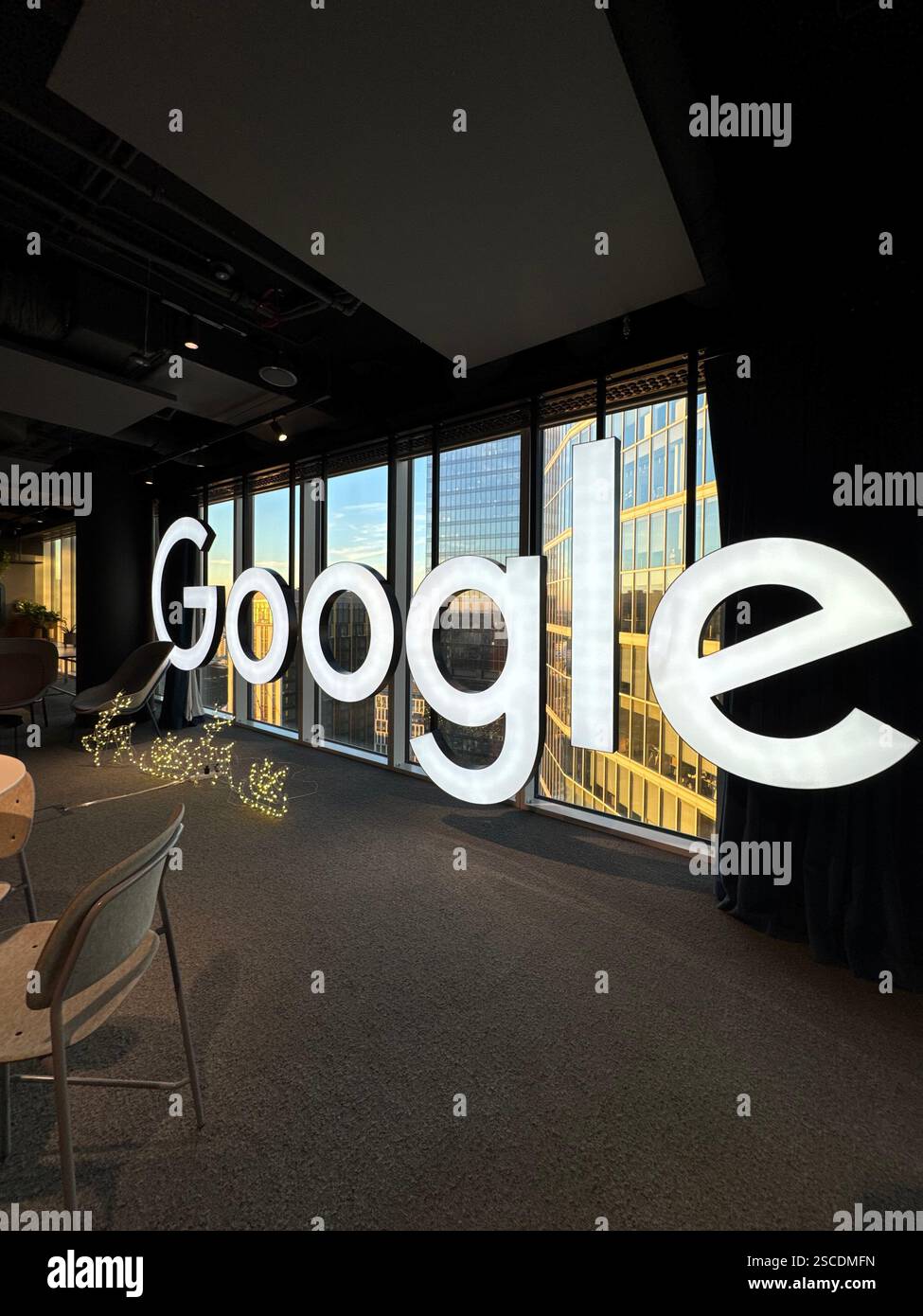 Google logo displayed in front of a glass window on the 30th floor of Google's office, offering a high-angle view of the city skyline. - Smartphone Captured Stock Image