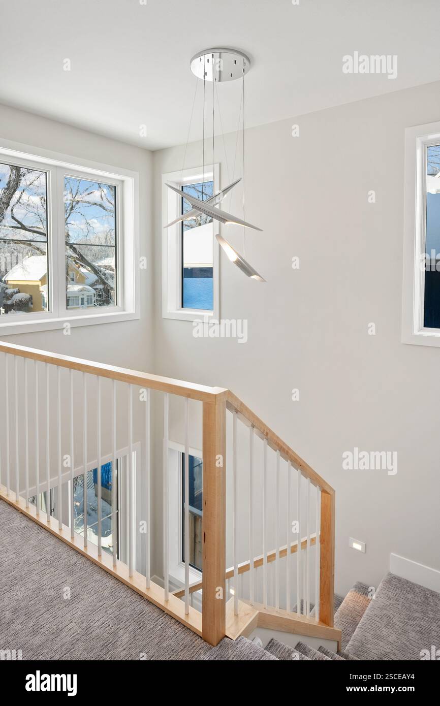 A staircase with a wooden railing and a light fixture hanging from the ...