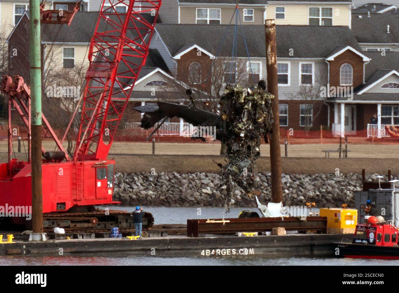 Rescue and salvage crews pull up a part of a Army Black Hawk helicopter ...