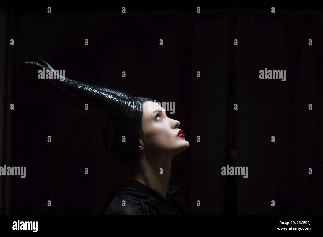 A figure with a horned headpiece looking upward in dramatic lighting Stock Photo