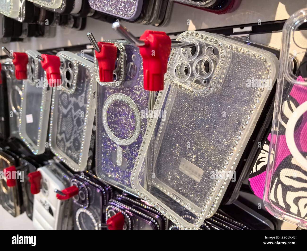 A wall display showcases an array of colorful phone cases glistening with sequins and rhinestones. Each case hangs neatly, attracting attention in a m Stock Photo