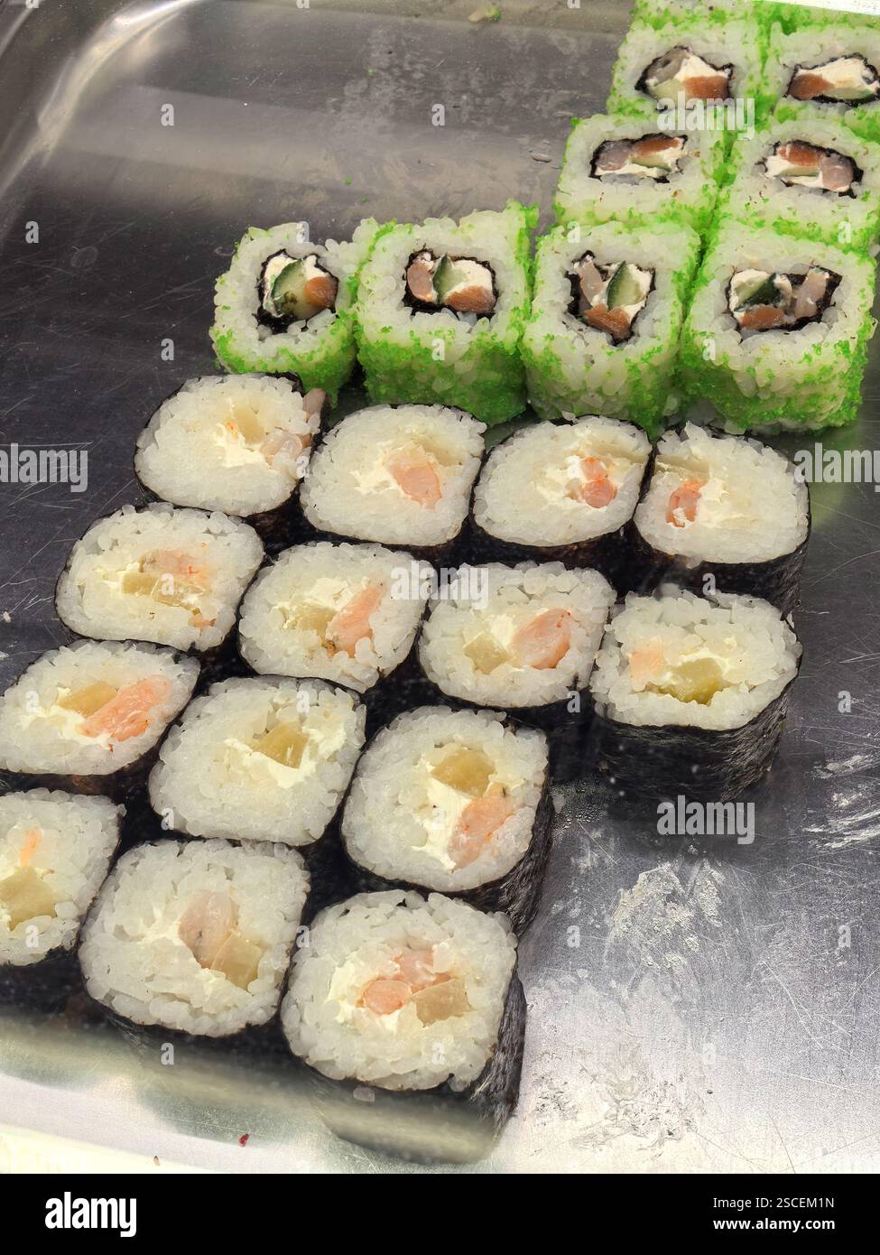 Brightly colored sushi rolls are artfully arranged on a stainless steel ...
