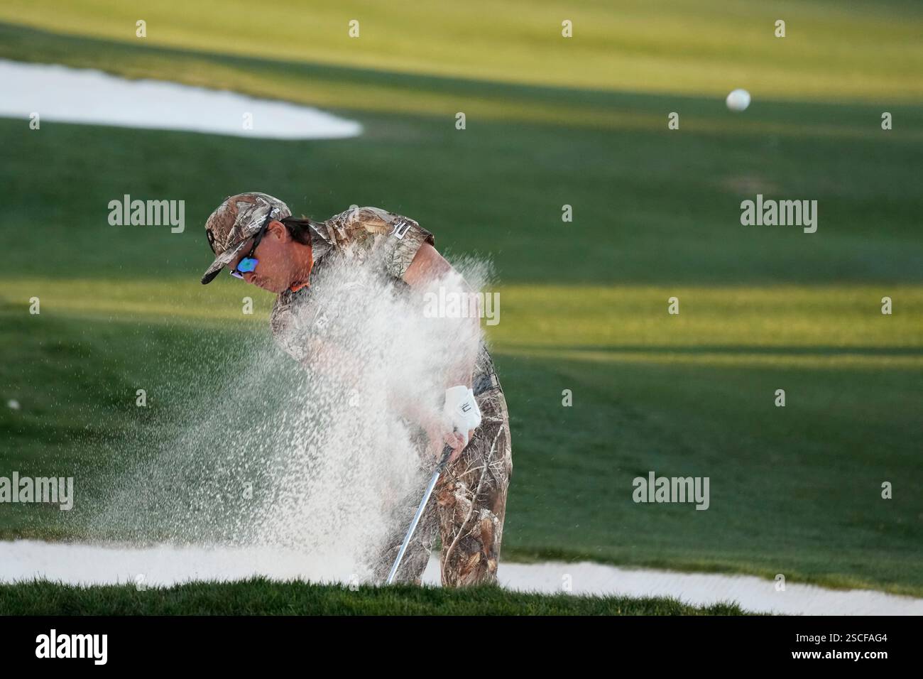 Rickie Fowler hits out of a fairway bunker at the 18th hole during the