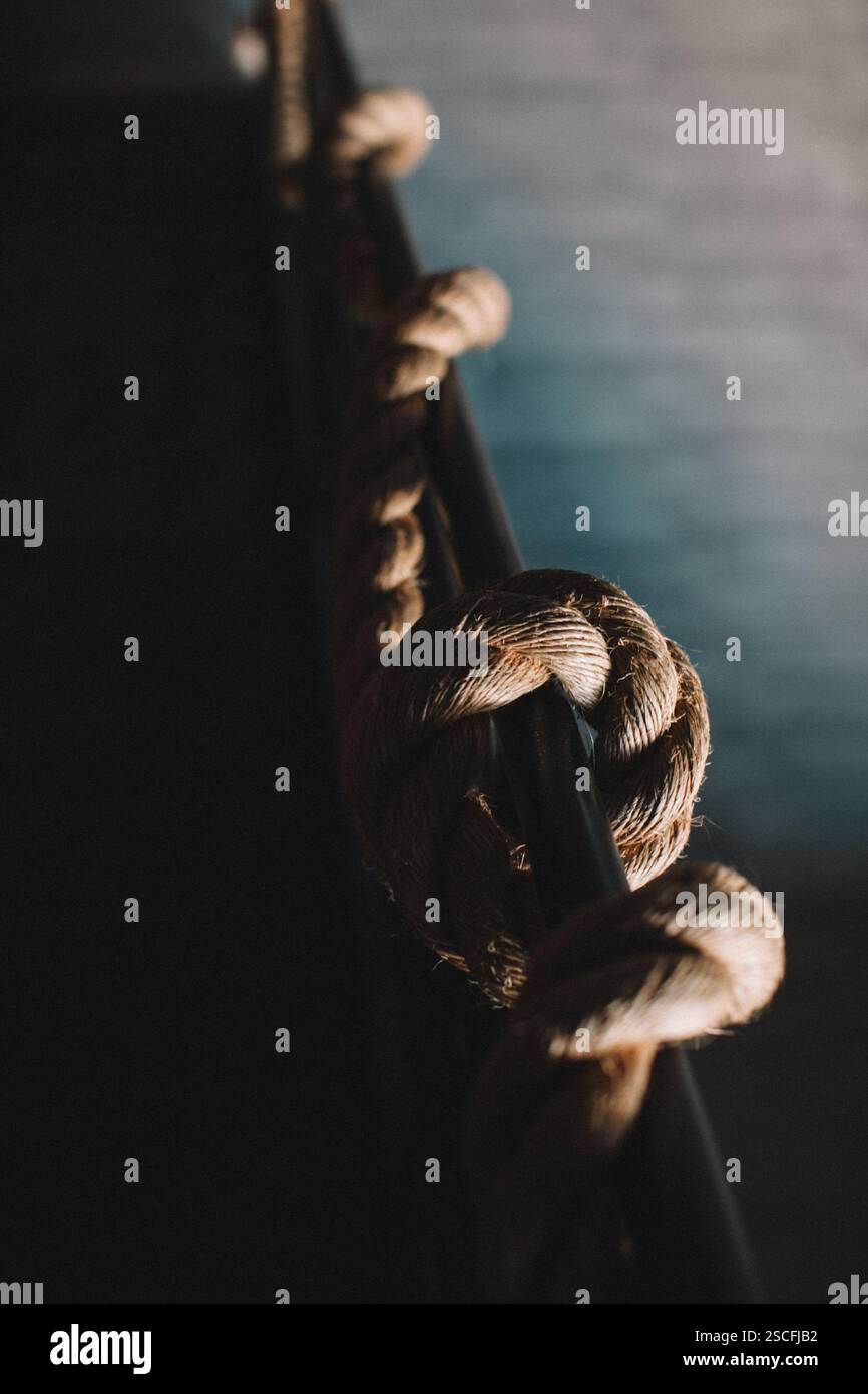 A close-up view of a natural rope beautifully knotted along a railing ...