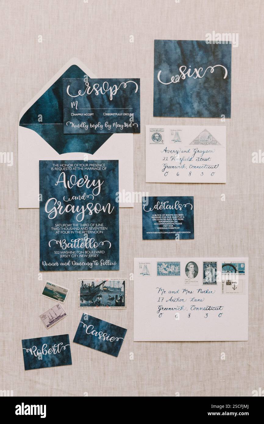 A beautifully arranged wedding invitation set, including RSVP cards and envelopes, showcasing a navy blue theme with elegant calligraphy. Decorative d Stock Photo