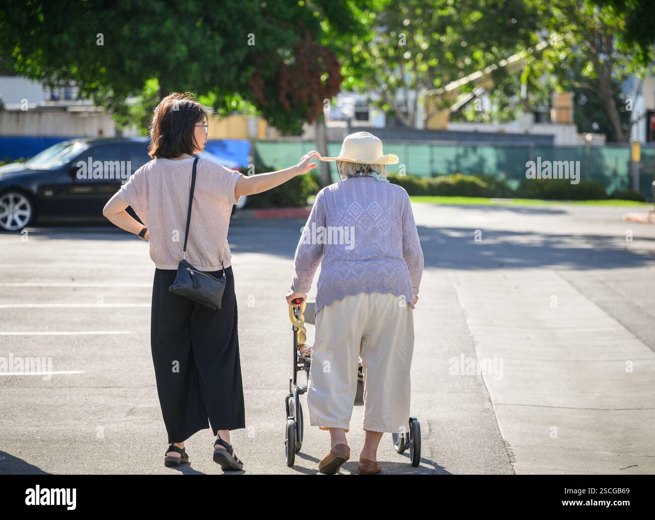 Senior woman walking using a mobility walker in the carpark. Adult ...