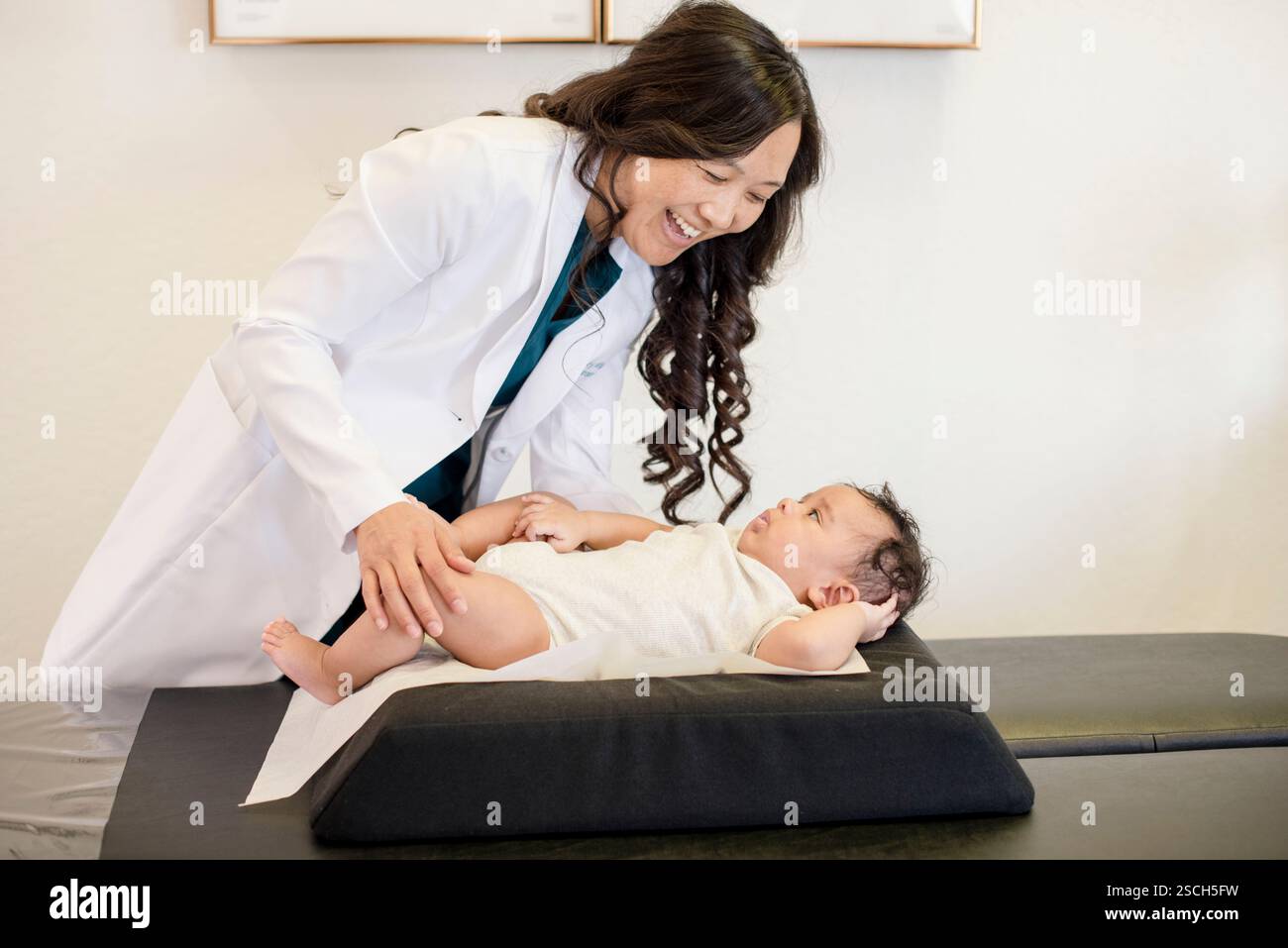Doctor evaluating baby laying down on back Stock Photo