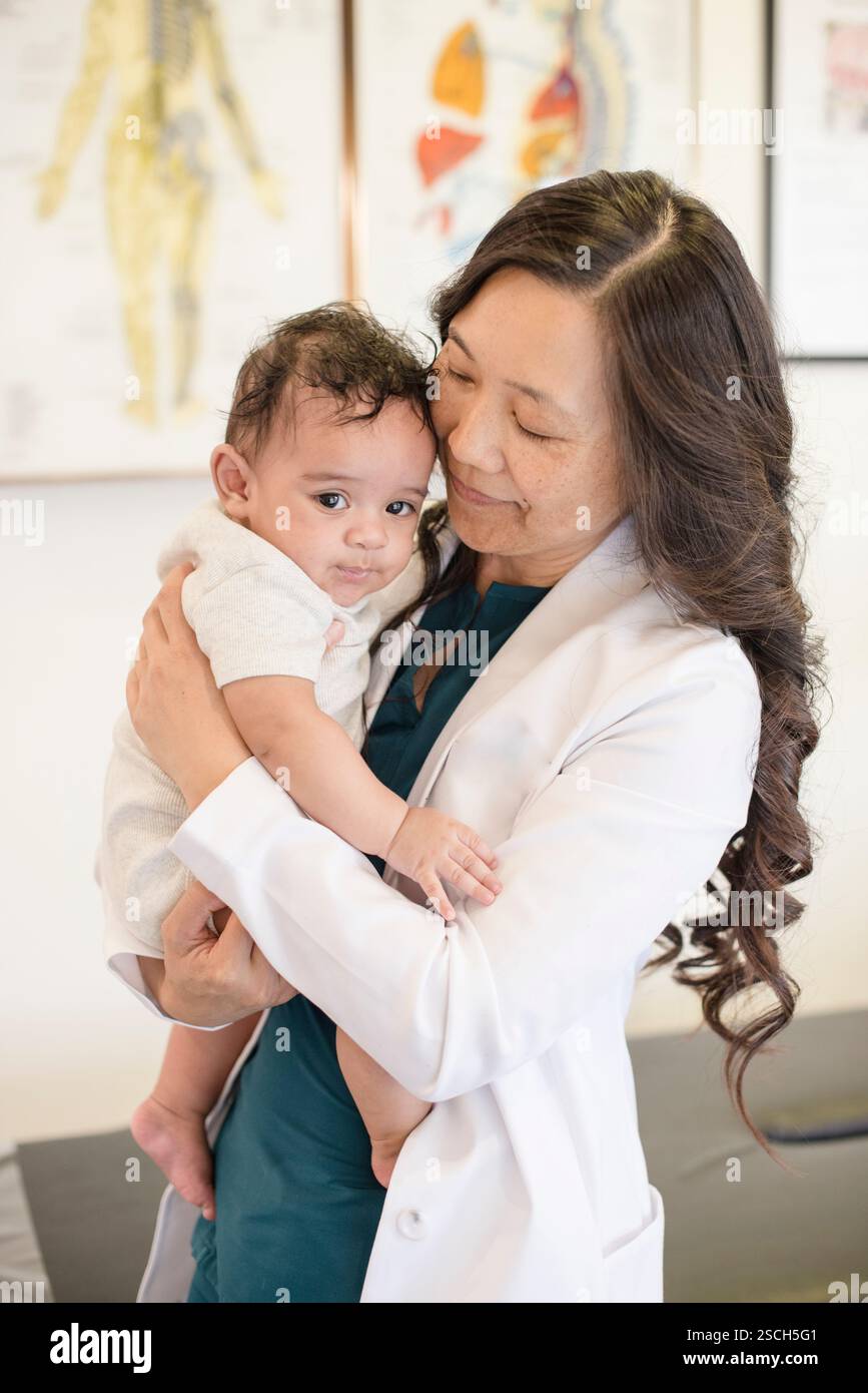Doctor holding baby patient in arms Stock Photo - Alamy