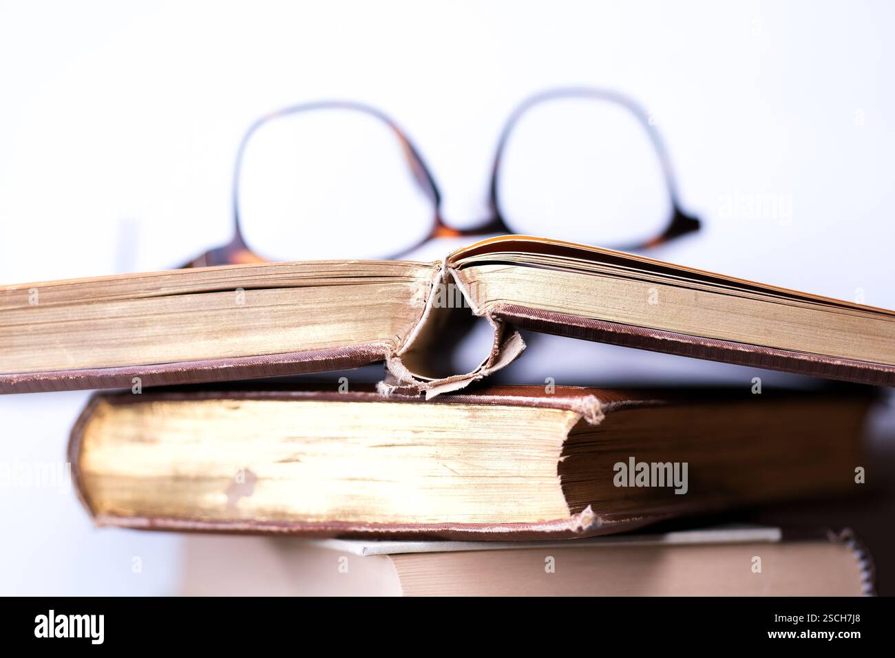 A stack of olf books and reading glasses Stock Photo