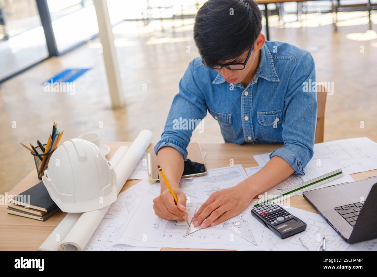 Architect working on blueprints at a modern workspace Stock Photo