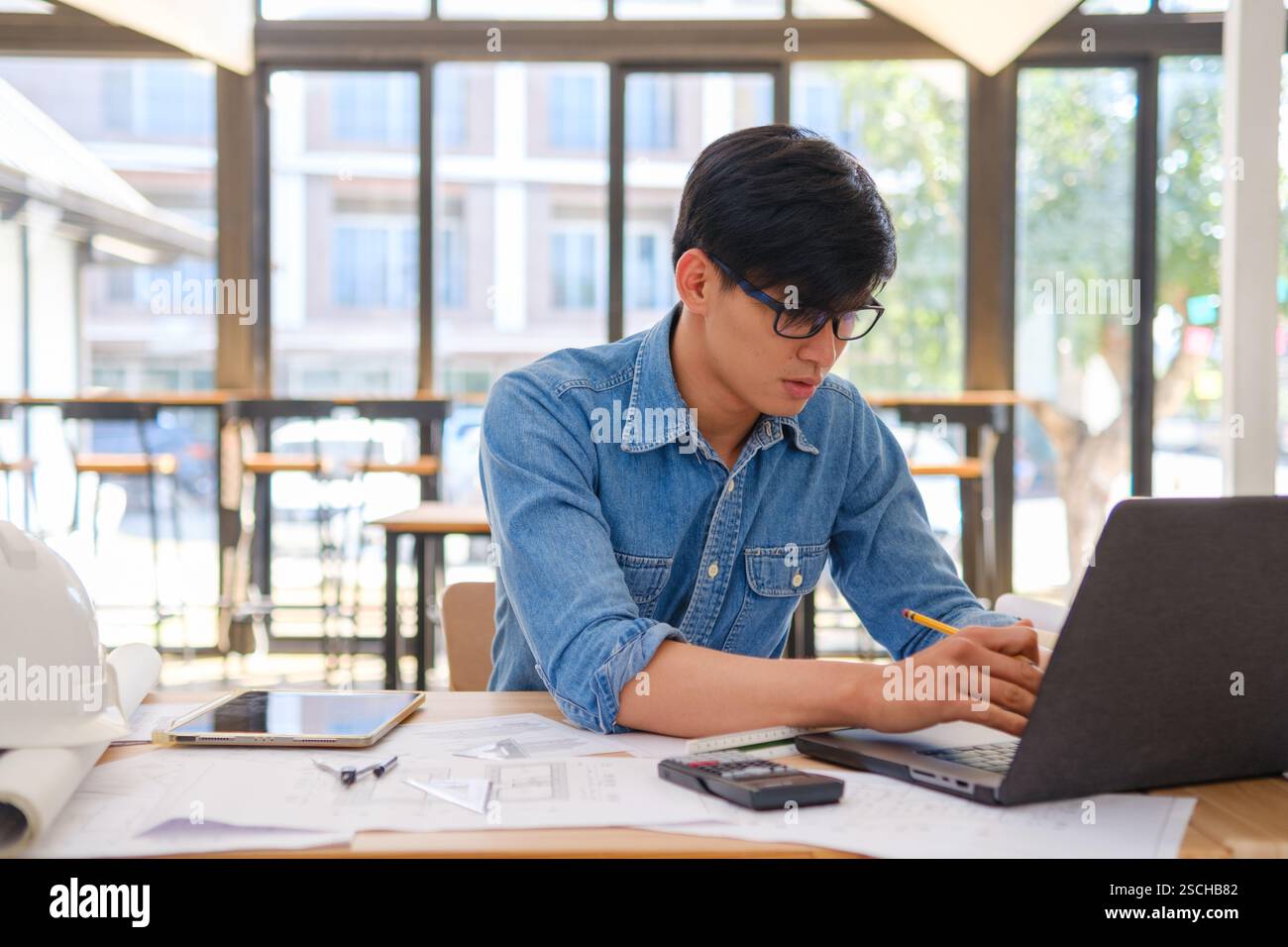 Architect working on blueprints at a modern workspace Stock Photo