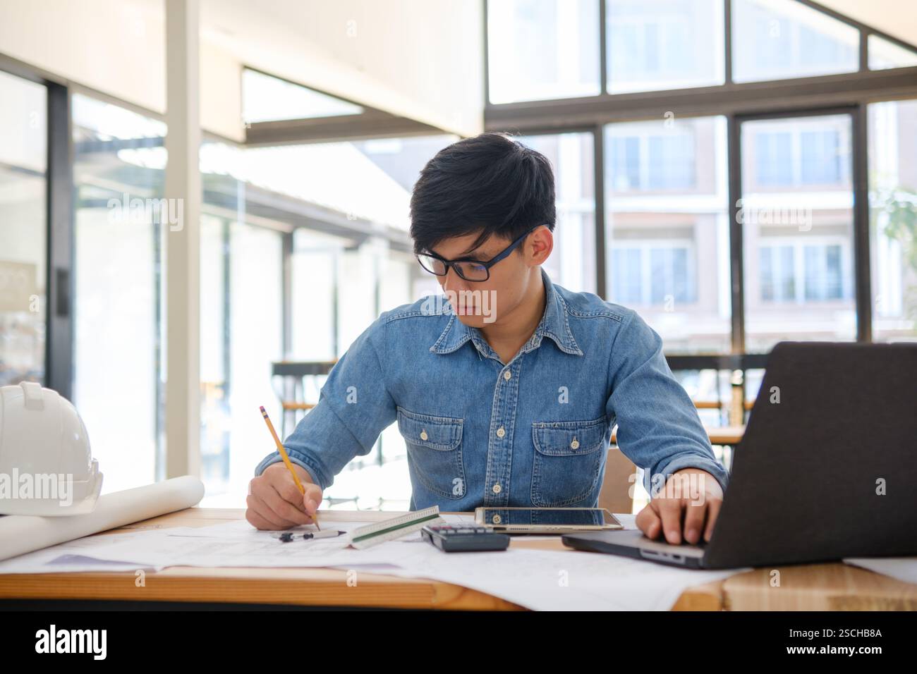 Architect working on blueprints at a modern workspace Stock Photo