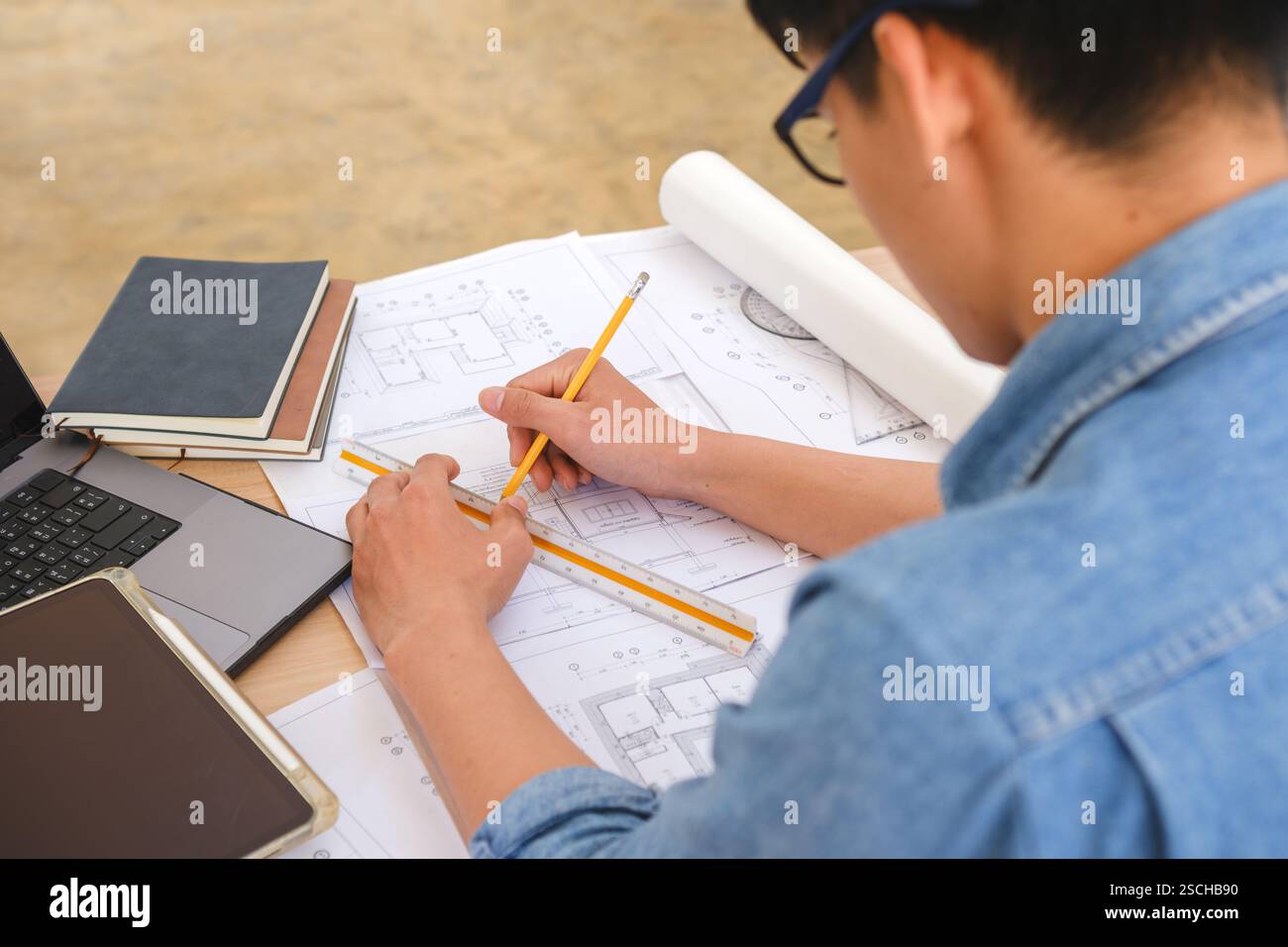 Architect working on blueprints at a modern workspace Stock Photo