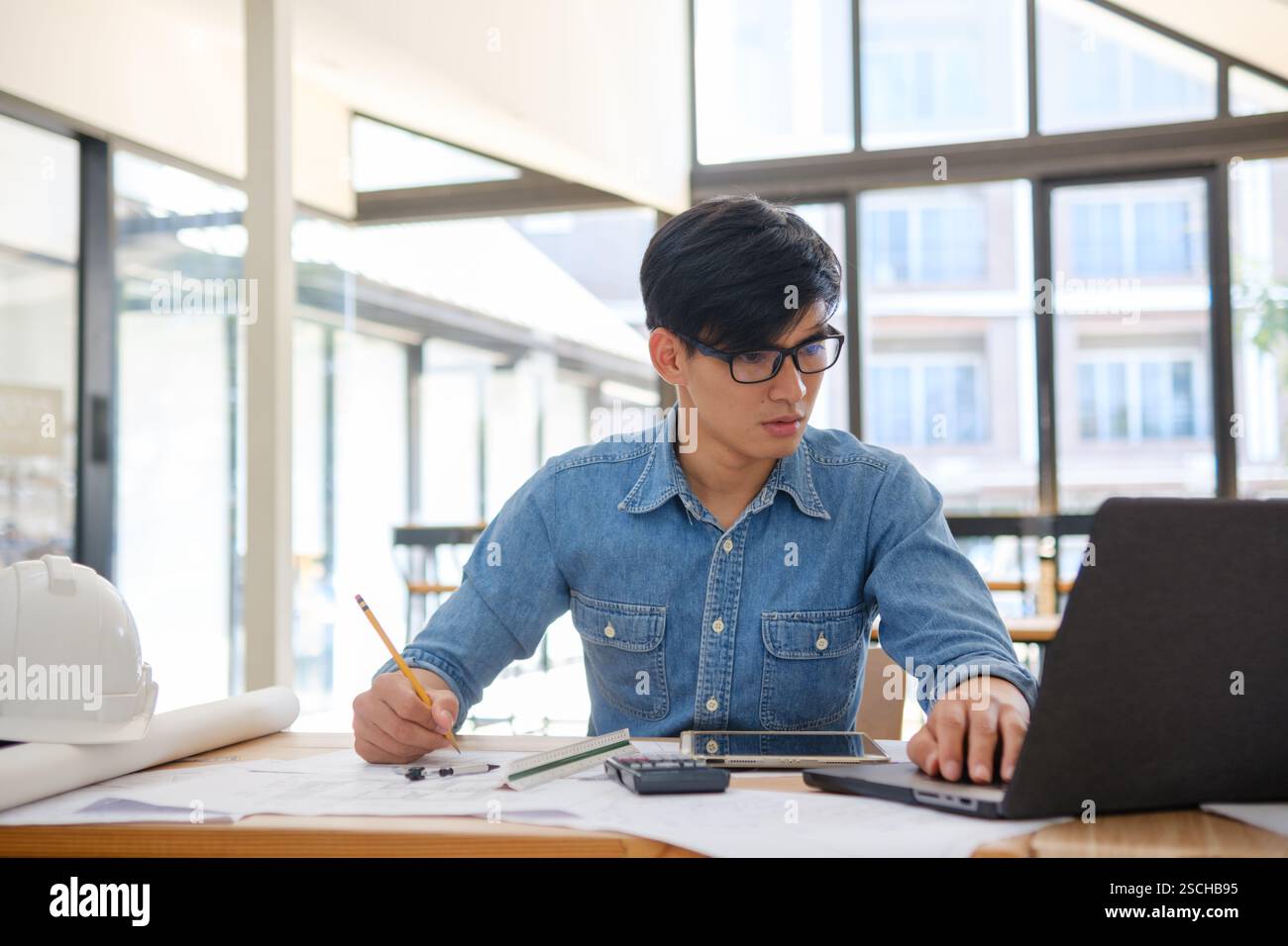 Architect working on blueprints at a modern workspace Stock Photo