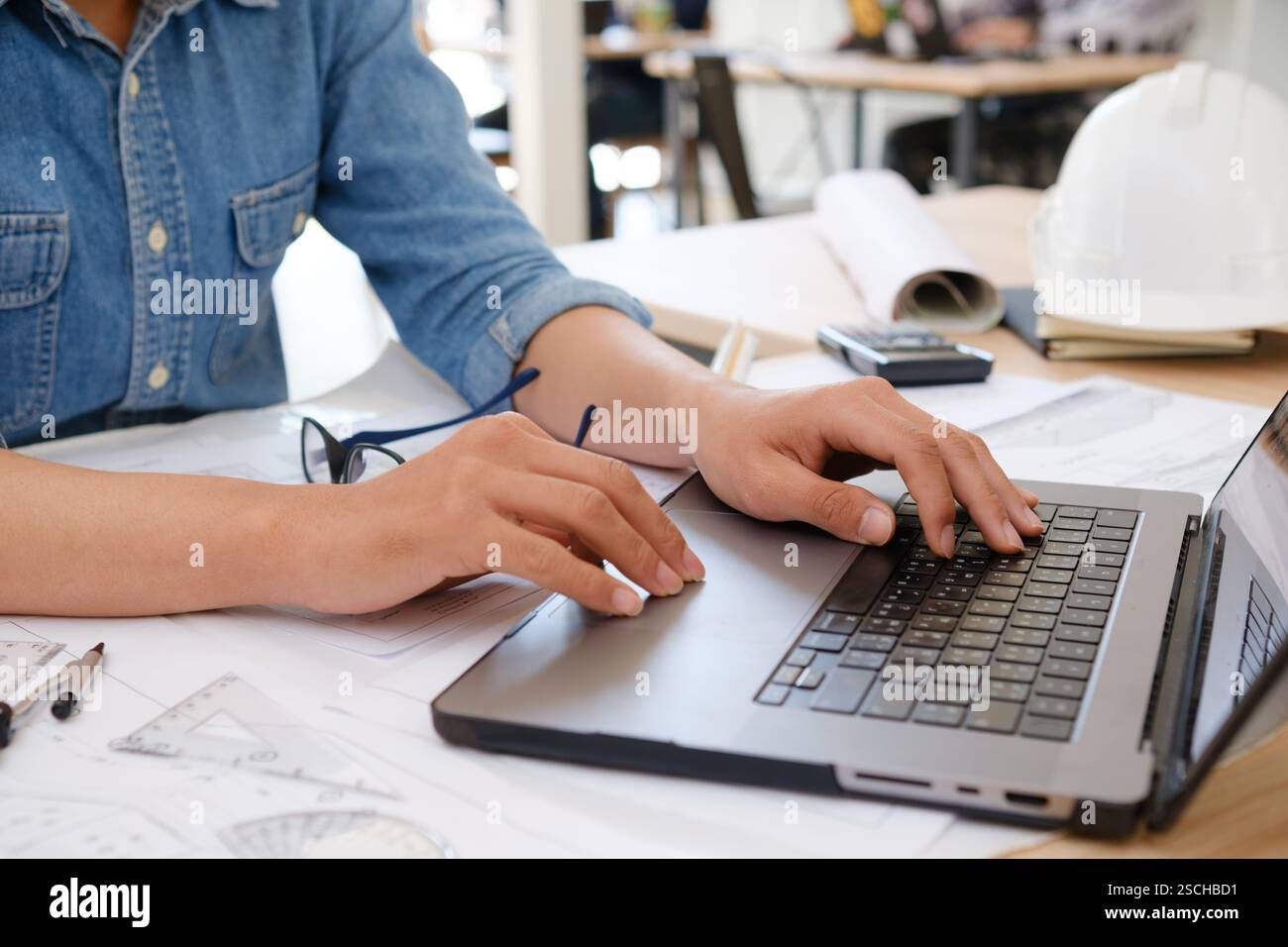 Architect and engineer working on a laptop with blueprints Stock Photo