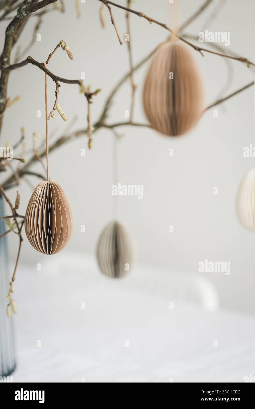 Easter paper eggs hanging on branches. Scandinavian-style Easter decorations. Stock Photo