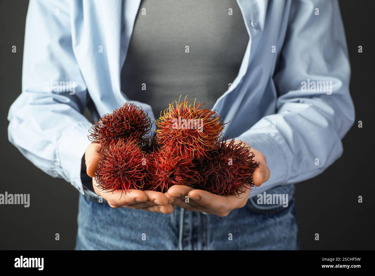 Woman holding fresh rambutans against black background, closeup Stock ...