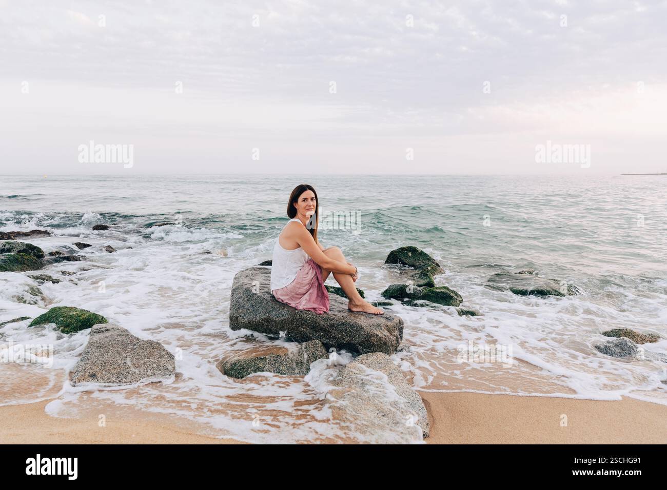 Woman seated on rocky beach hi-res stock photography and images - Alamy