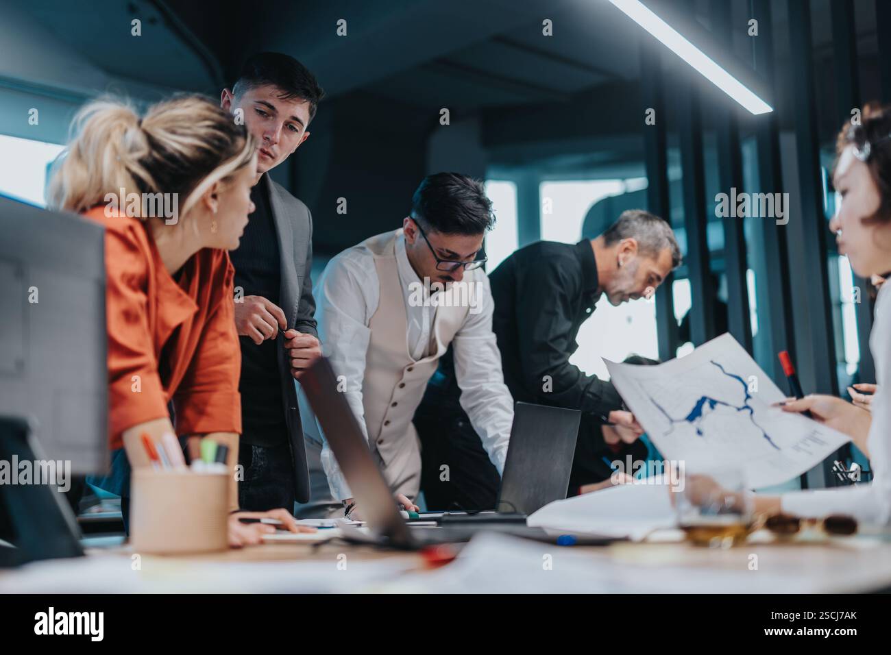 A group of diverse business people gathers around a table ...