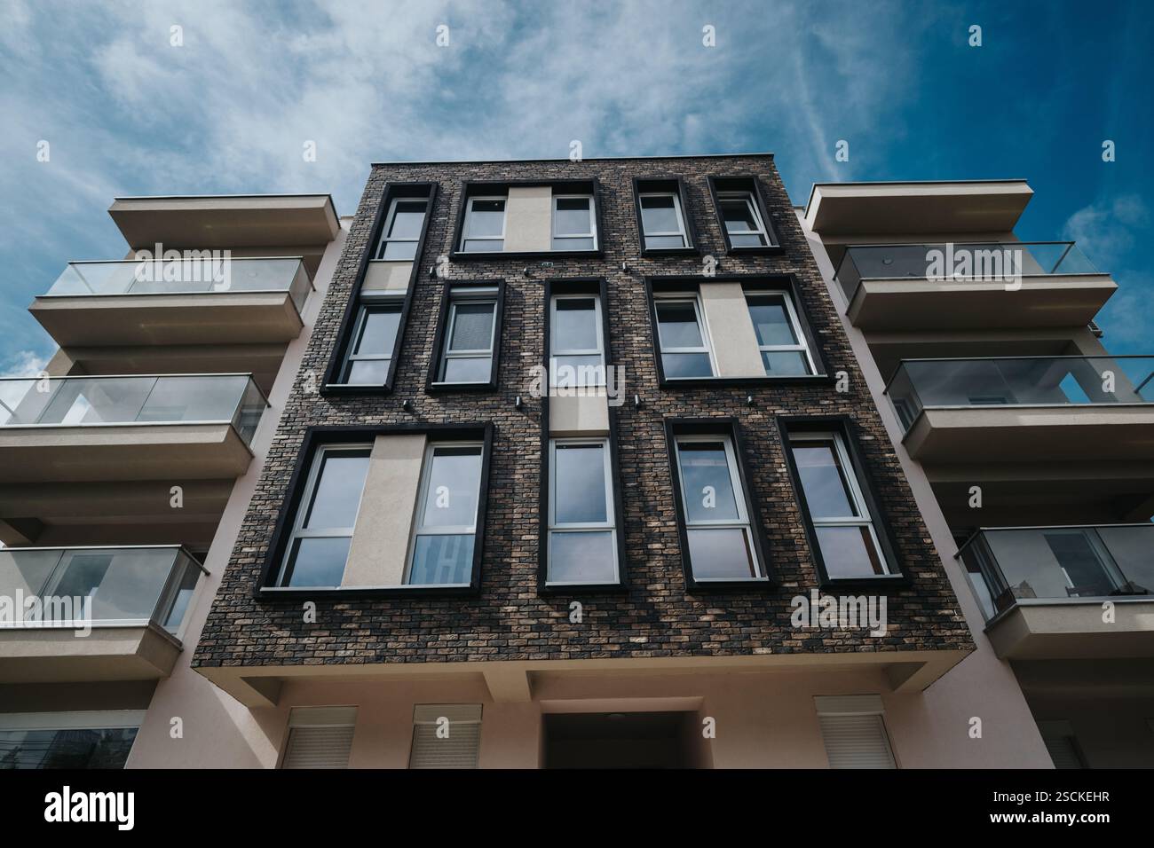 Modern apartment building with brick facade and glass balconies on a ...