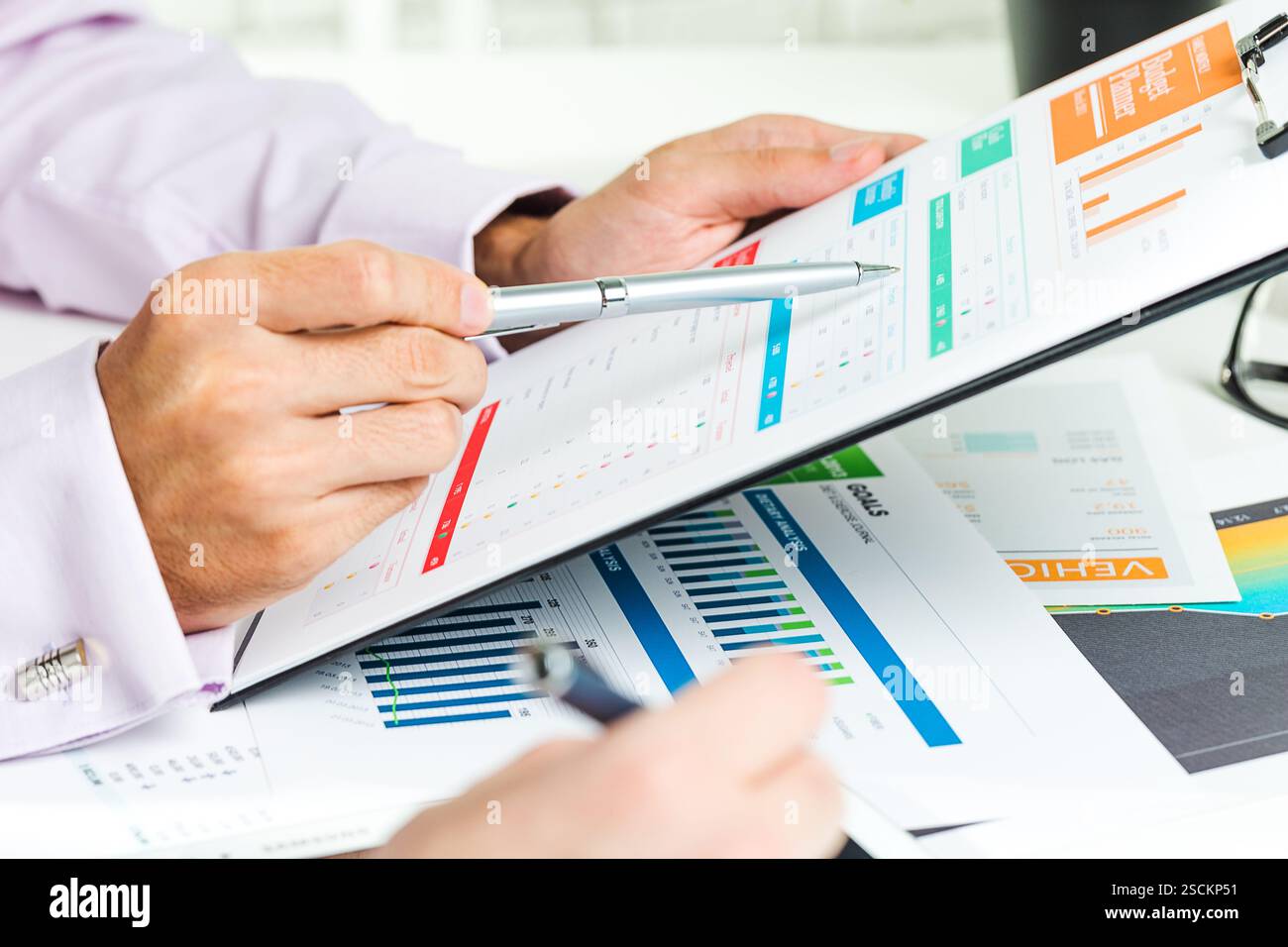 Hands analyzing business reports with charts and graphs in an office ...