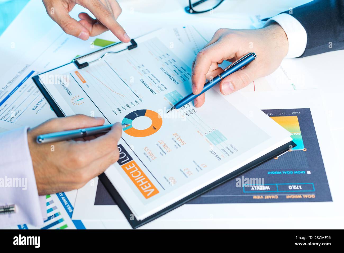 Hands analyzing business charts and graphs during a meeting in a modern ...
