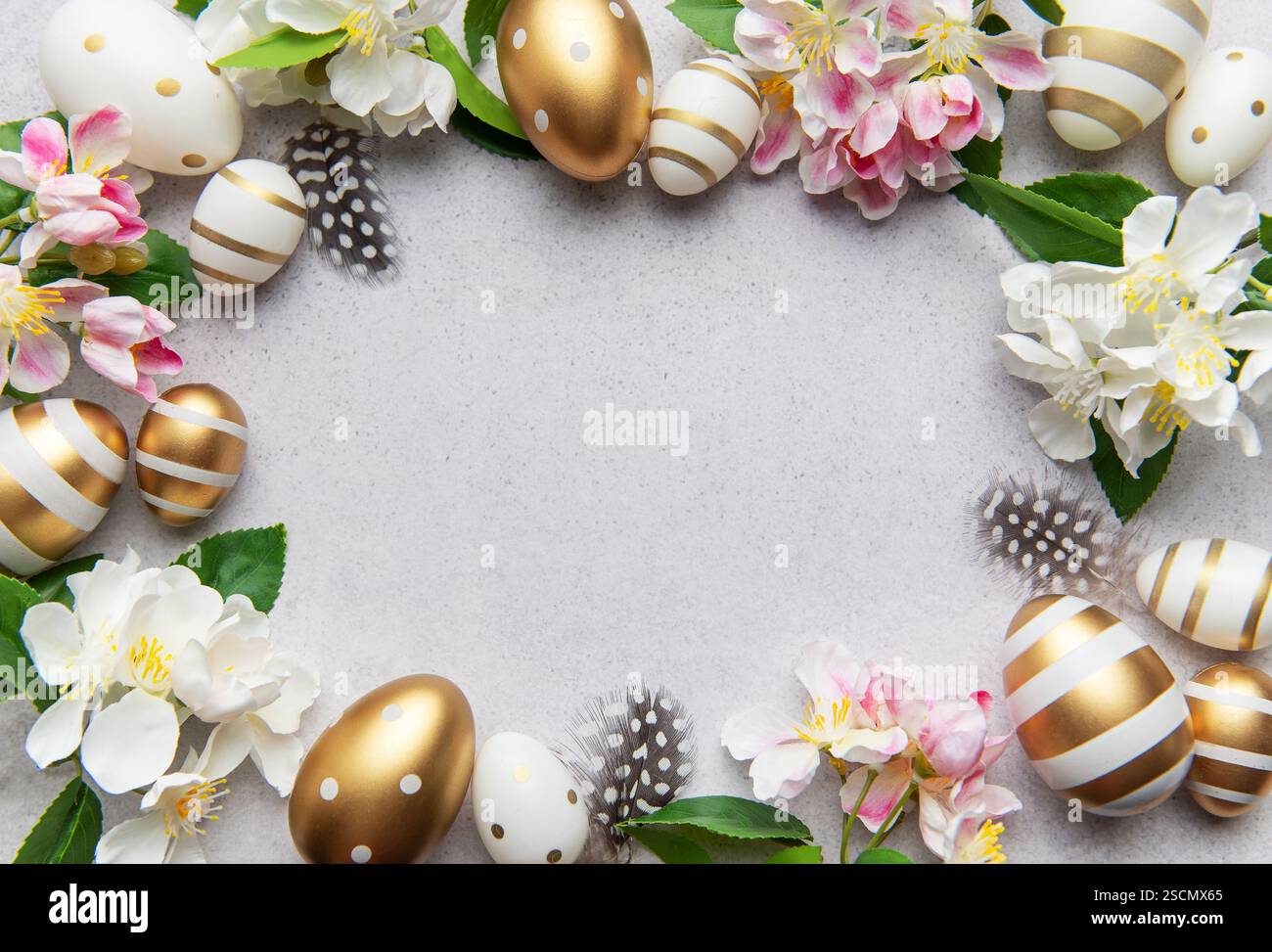 Golden eggs and flowers create a festive easter border on a light background Stock Photo