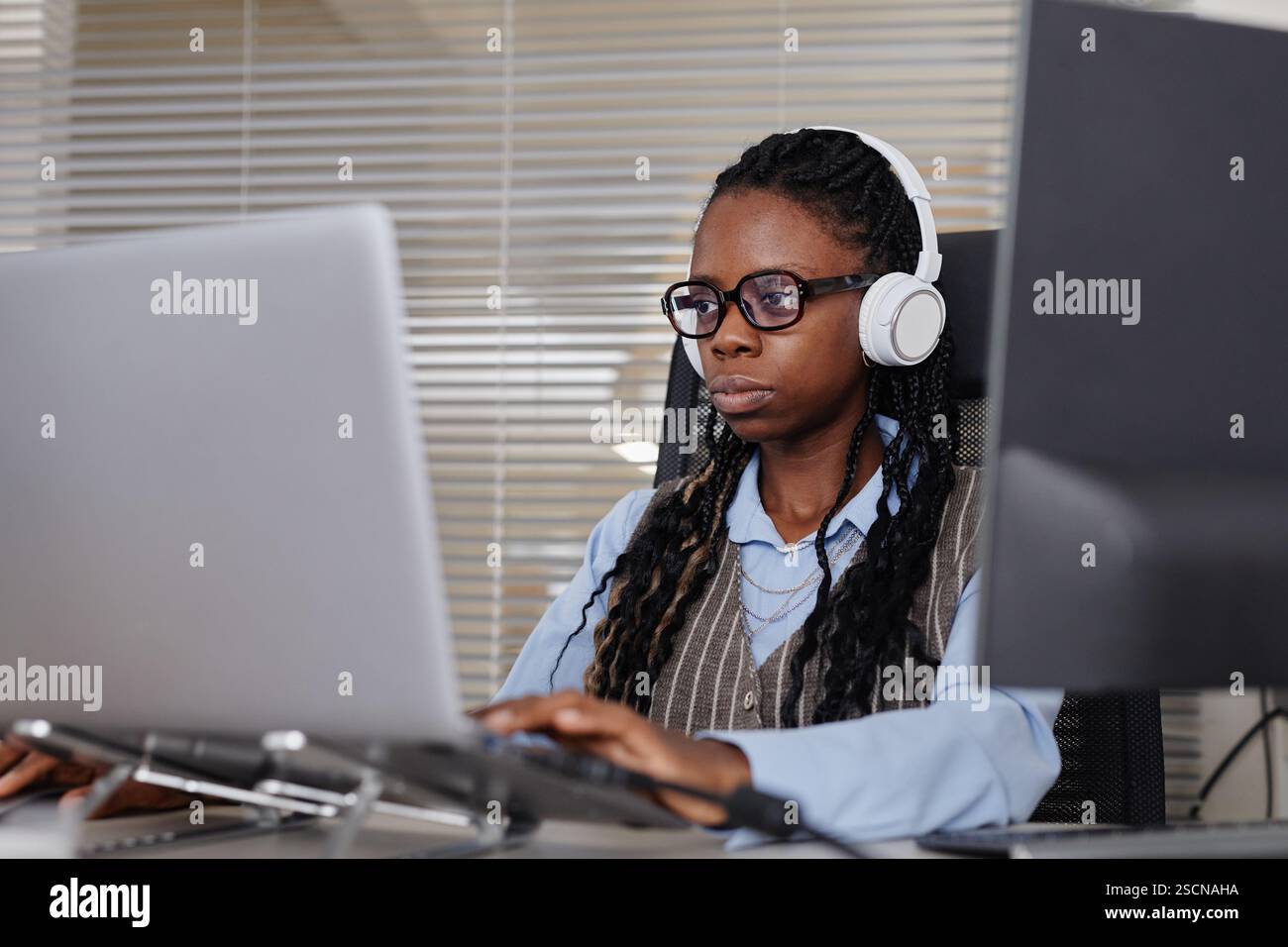 Portrait of woman wearing headphones and working on computer in an ...
