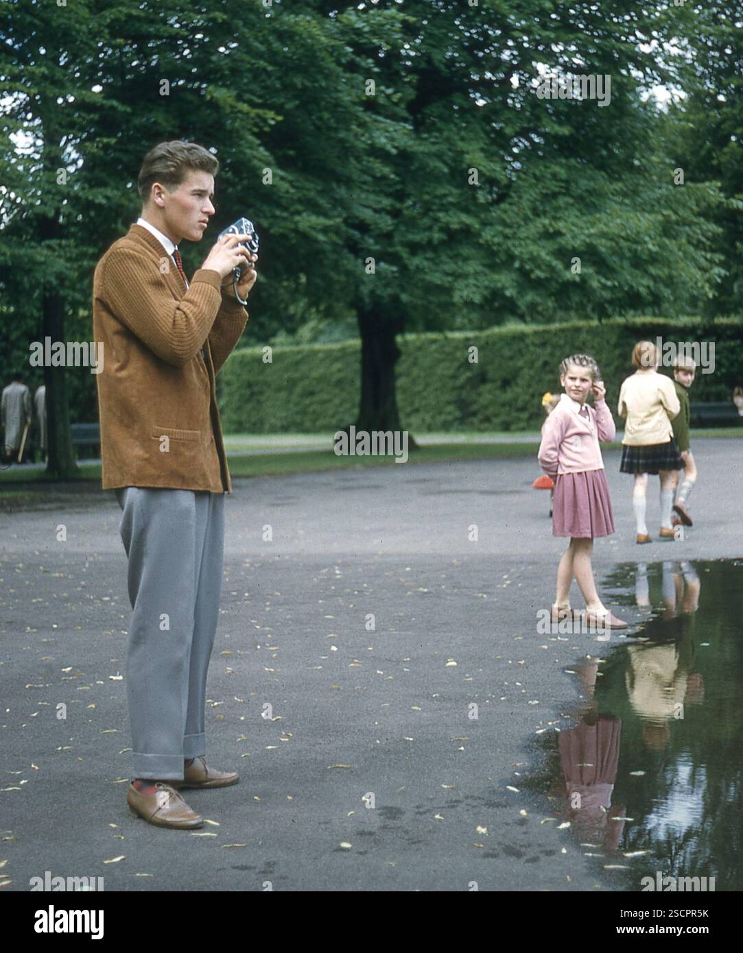 A man takes a photo of something in the distance. Next to him is a ...