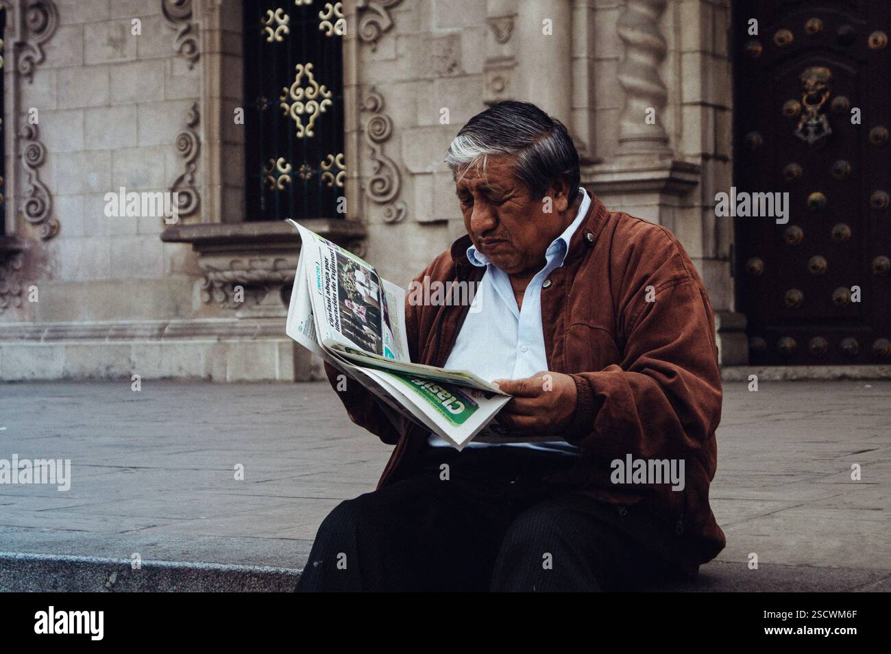 Man Reading a Newspaper in Front of Colonial Cathedral – Centro de Lima Stock Photo