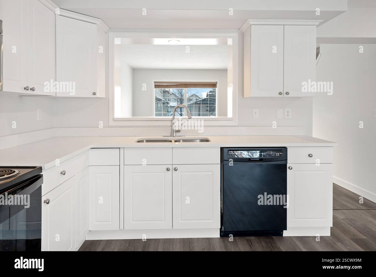 A kitchen with a black dishwasher and white cabinets. The kitchen is ...