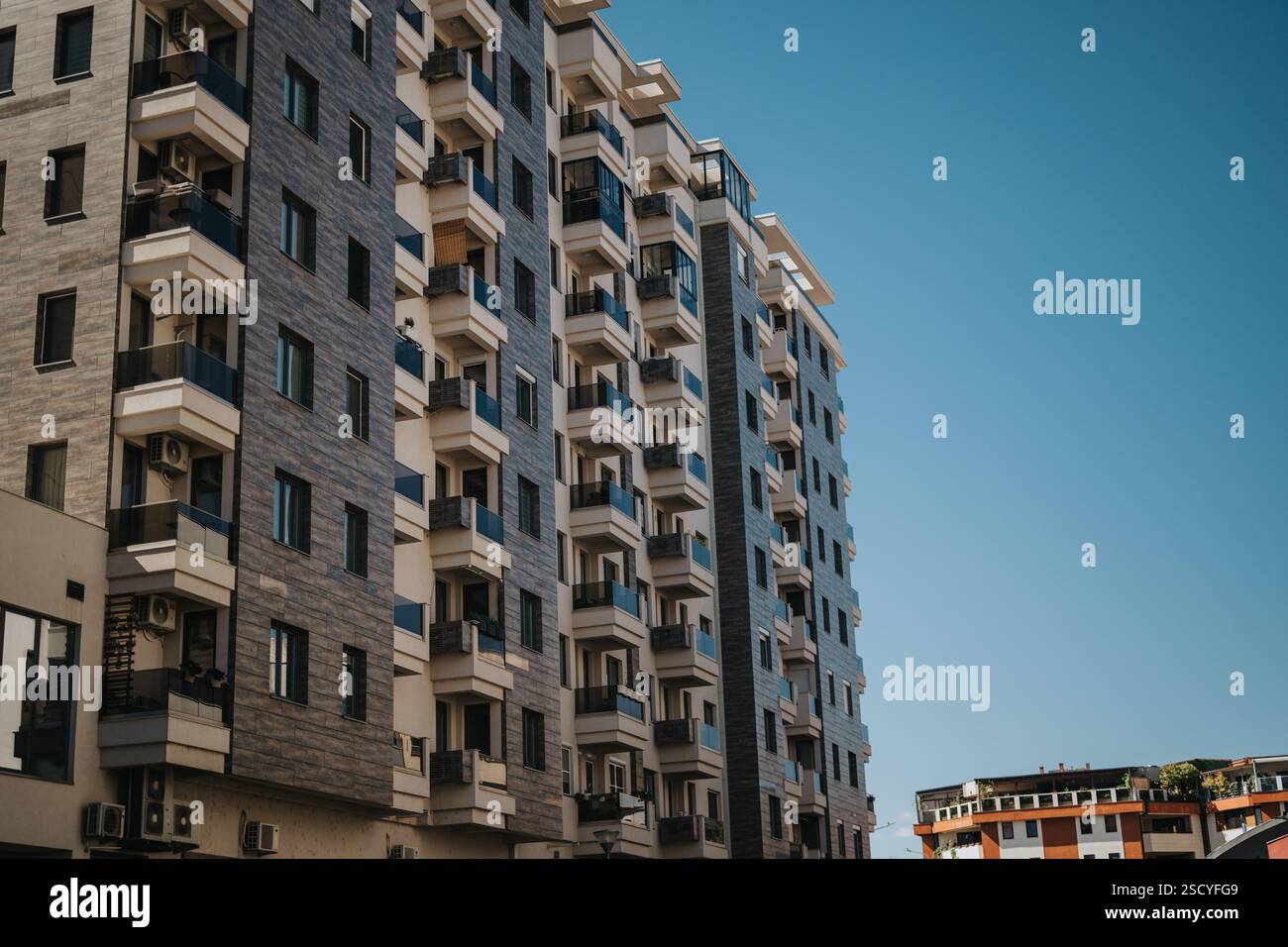 Modern apartment building exterior with balconies against a clear blue ...